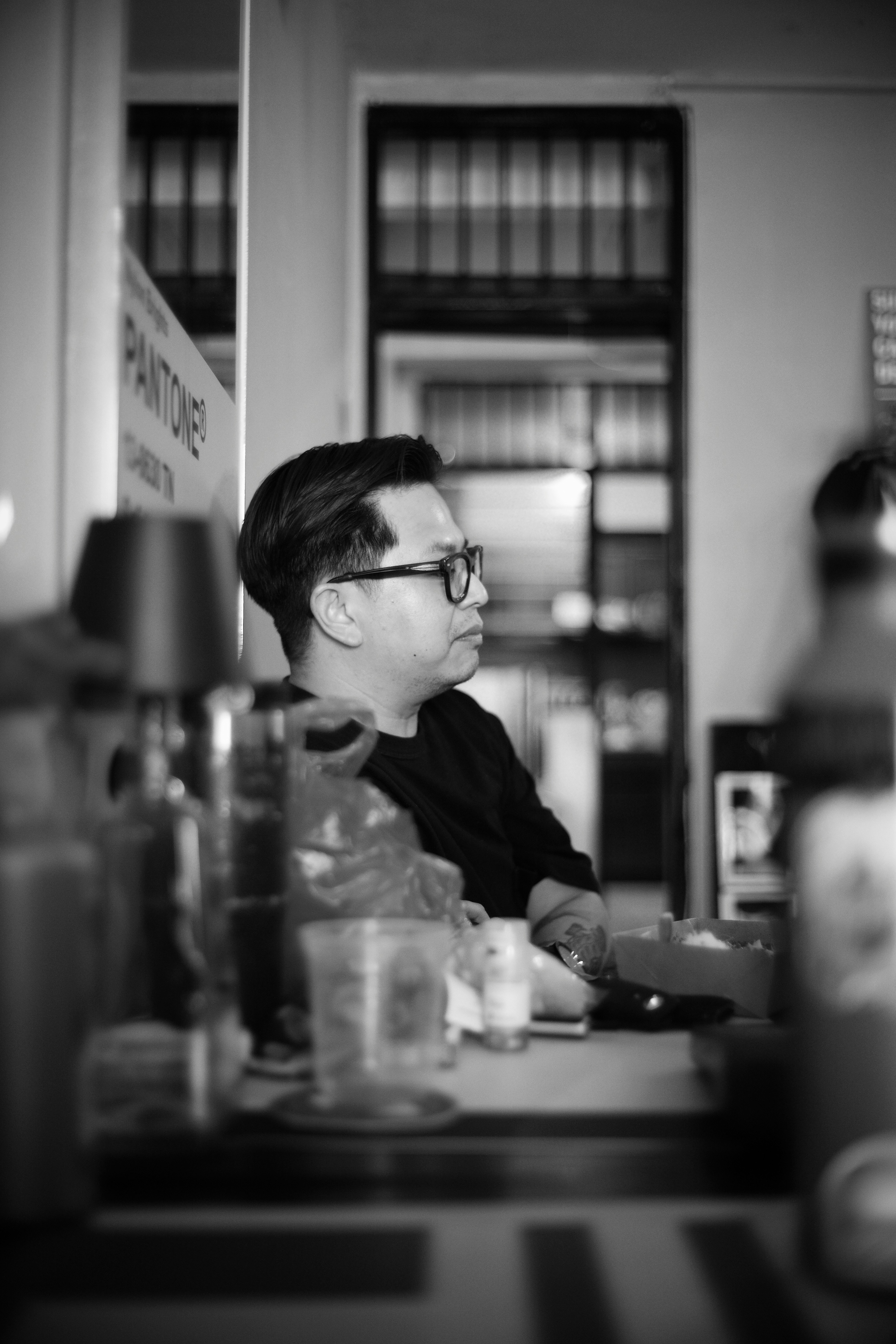 A man with glasses in a black t-shirt at a table in a room