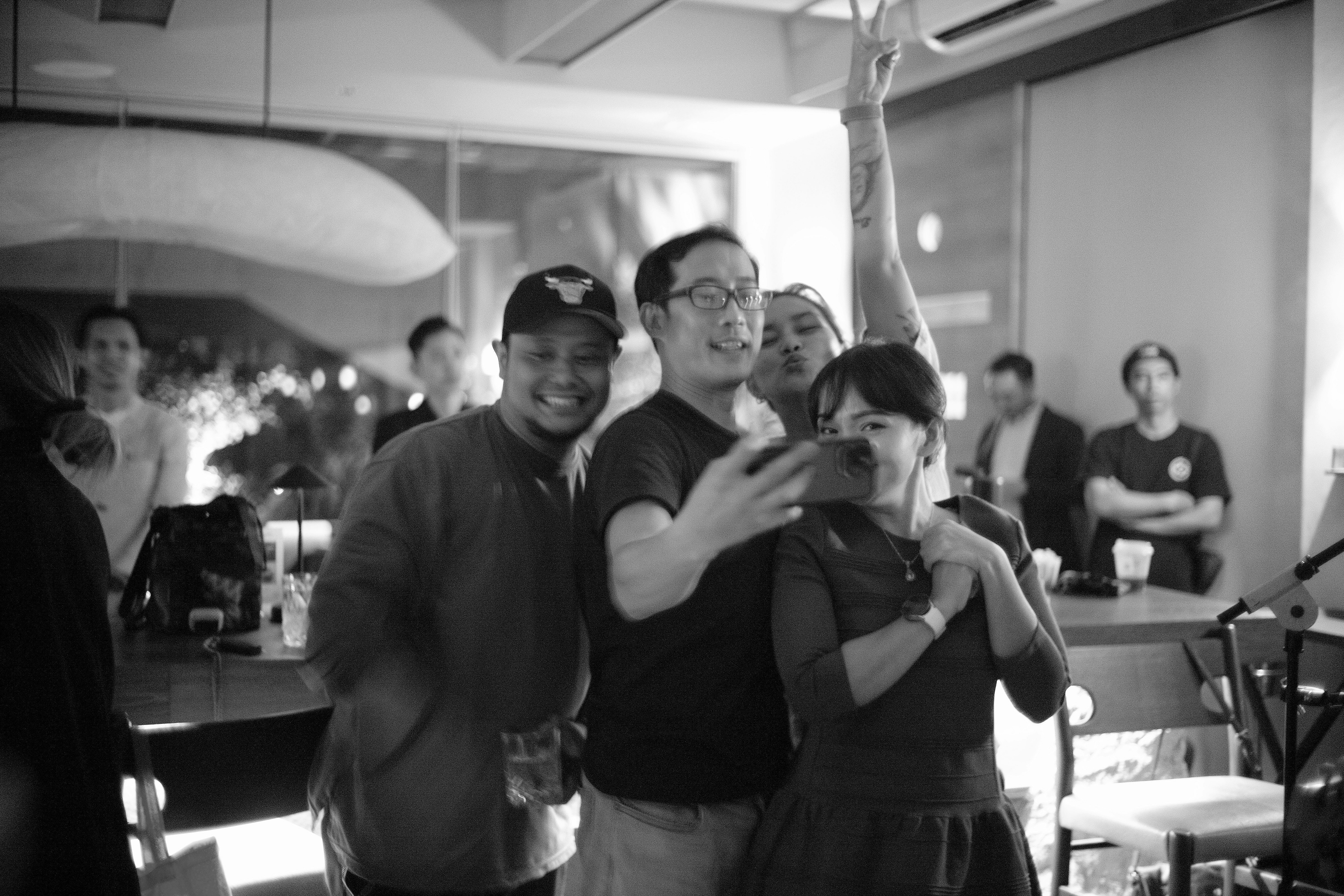 A group of friends squeezing into a selfie in a dim restaurant