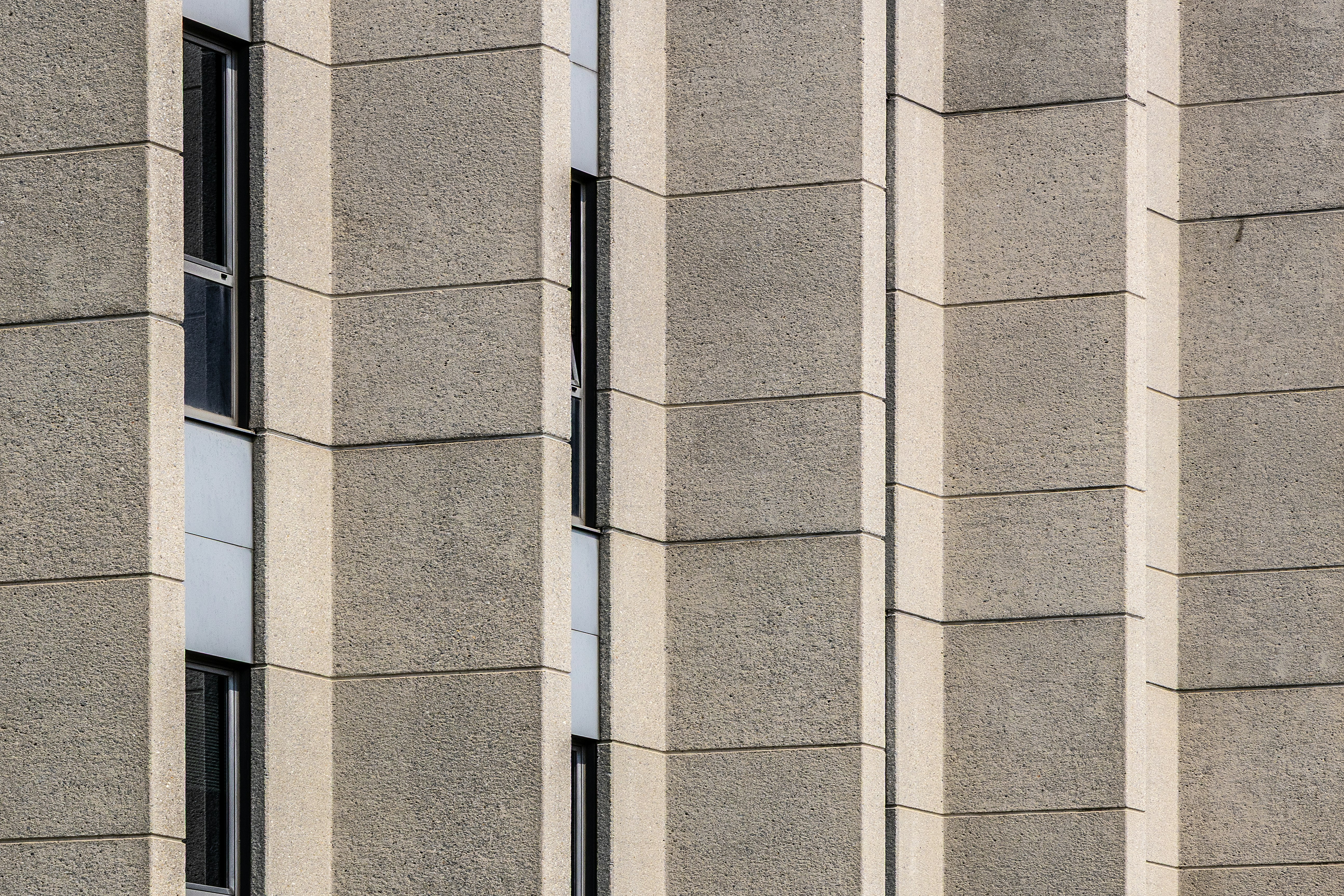 Une façade texturée en béton avec colonnes verticales et fenêtres en retrait