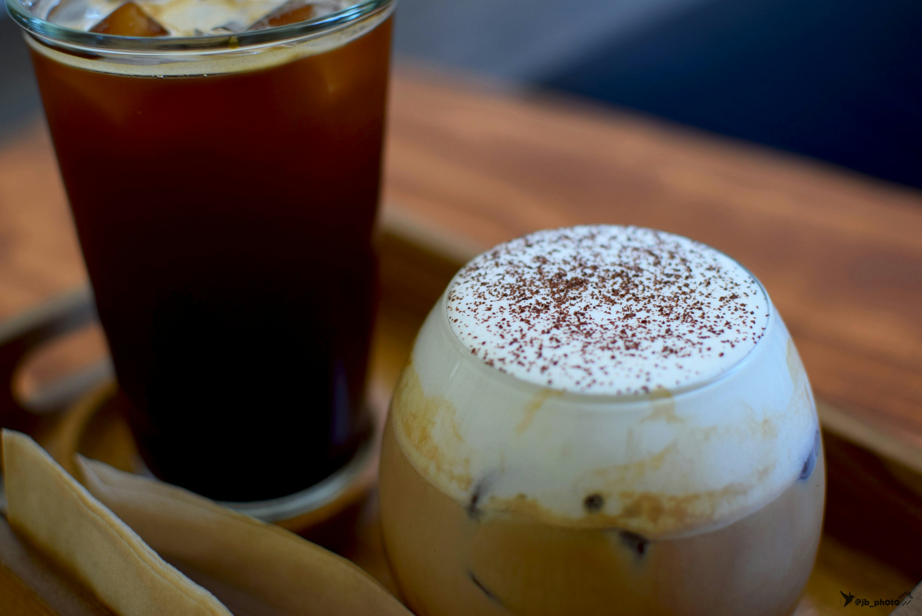 Iced coffee beside a cream-topped drink