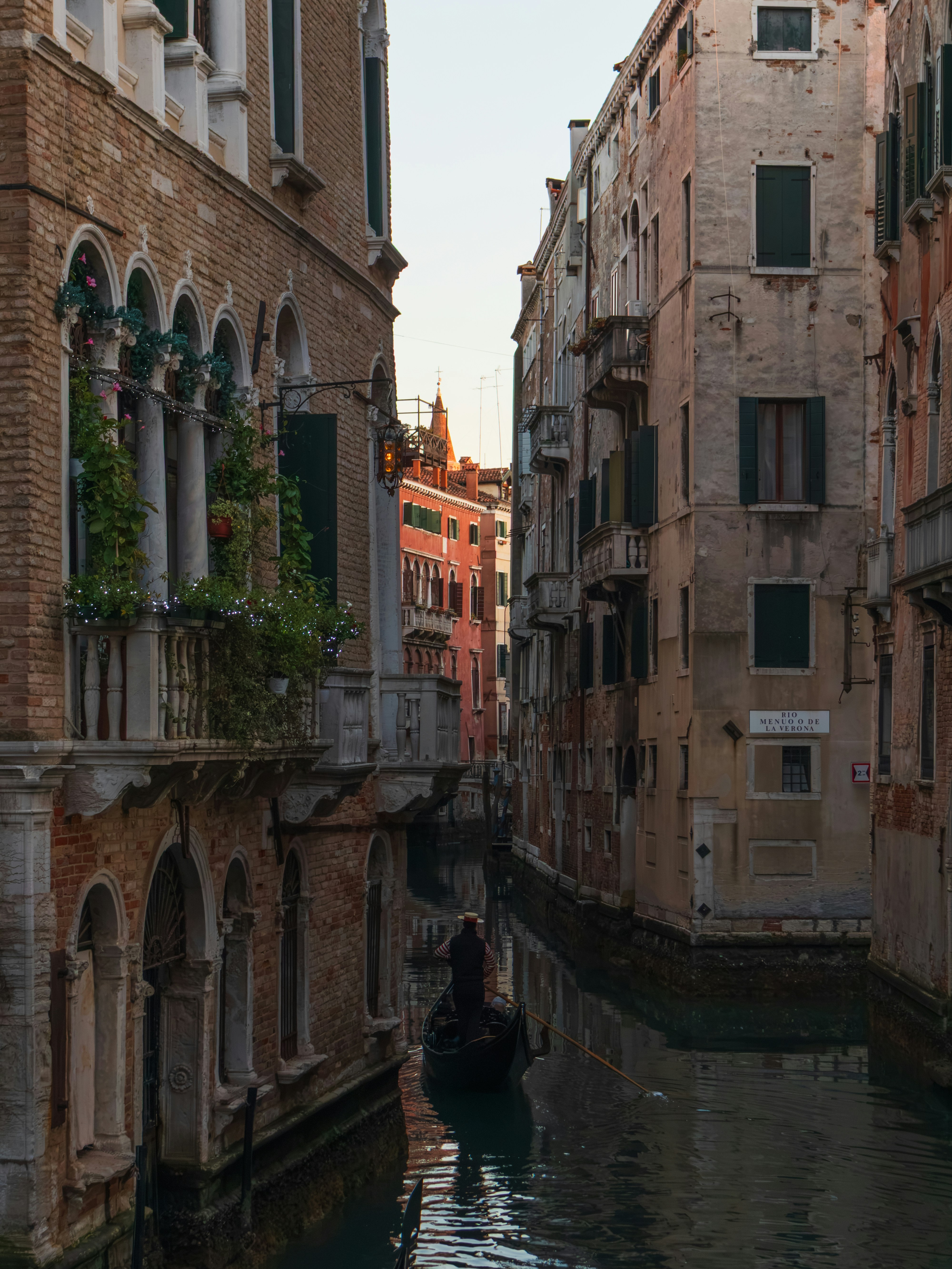 A gondolier rowing a gondola through a narrow canal in Venice, Italy