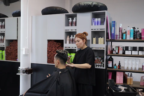 A woman cutting a man's hair with clippers in a hair salon