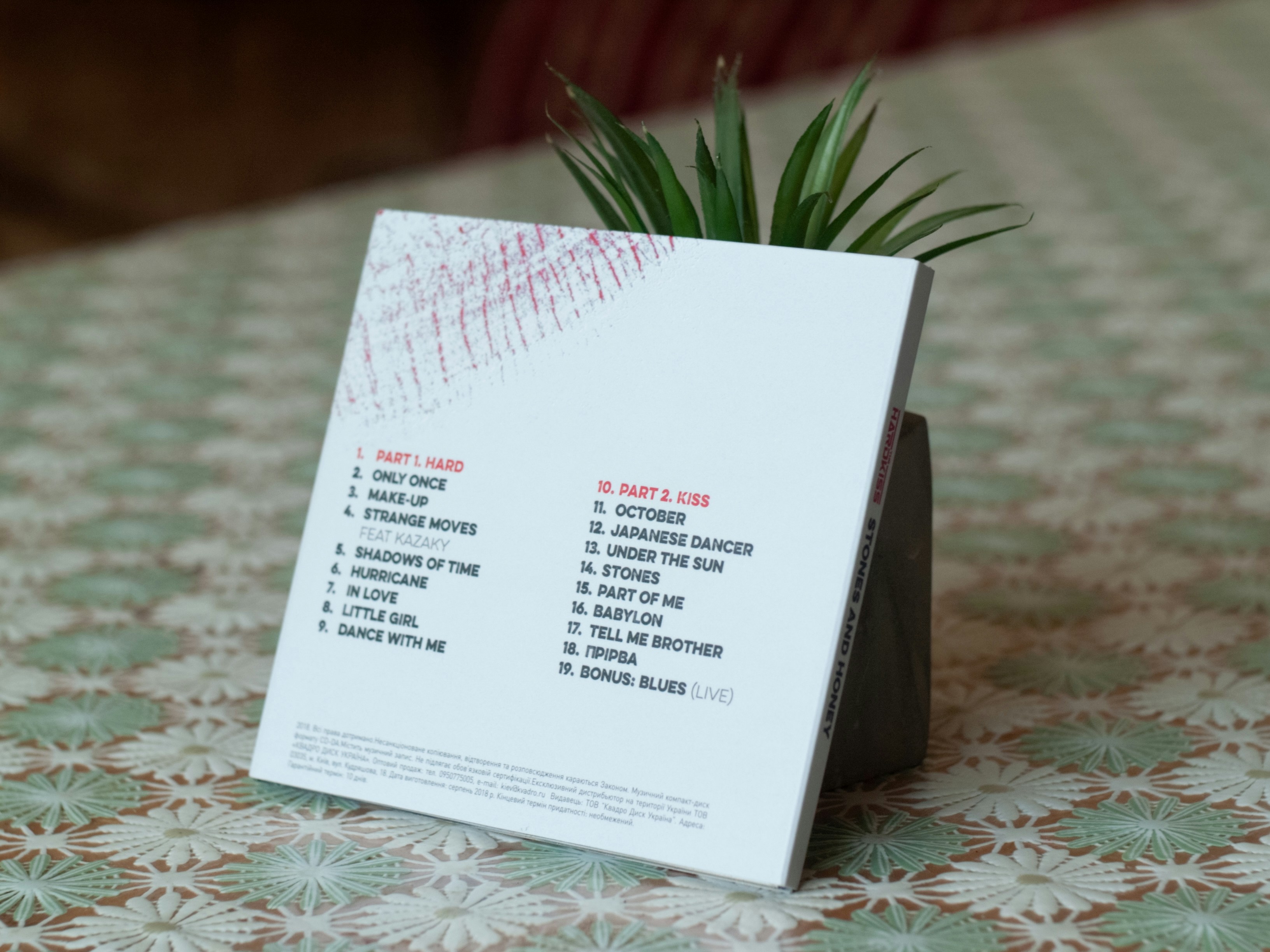 A music album case with a tracklist and a small plant behind it