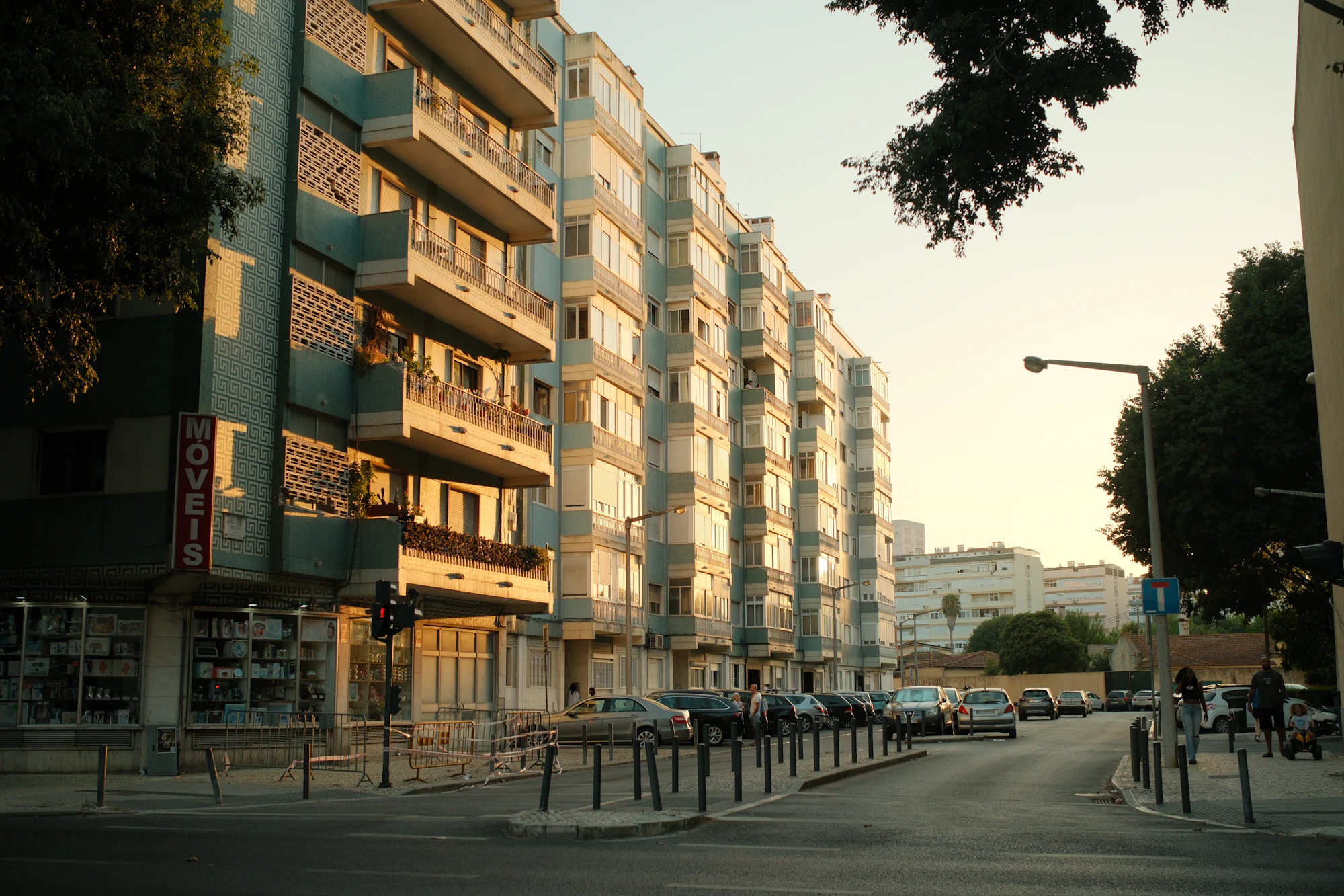 Apartment buildings and a neighborhood street in Benfica, Lisbon, in warm evening light.