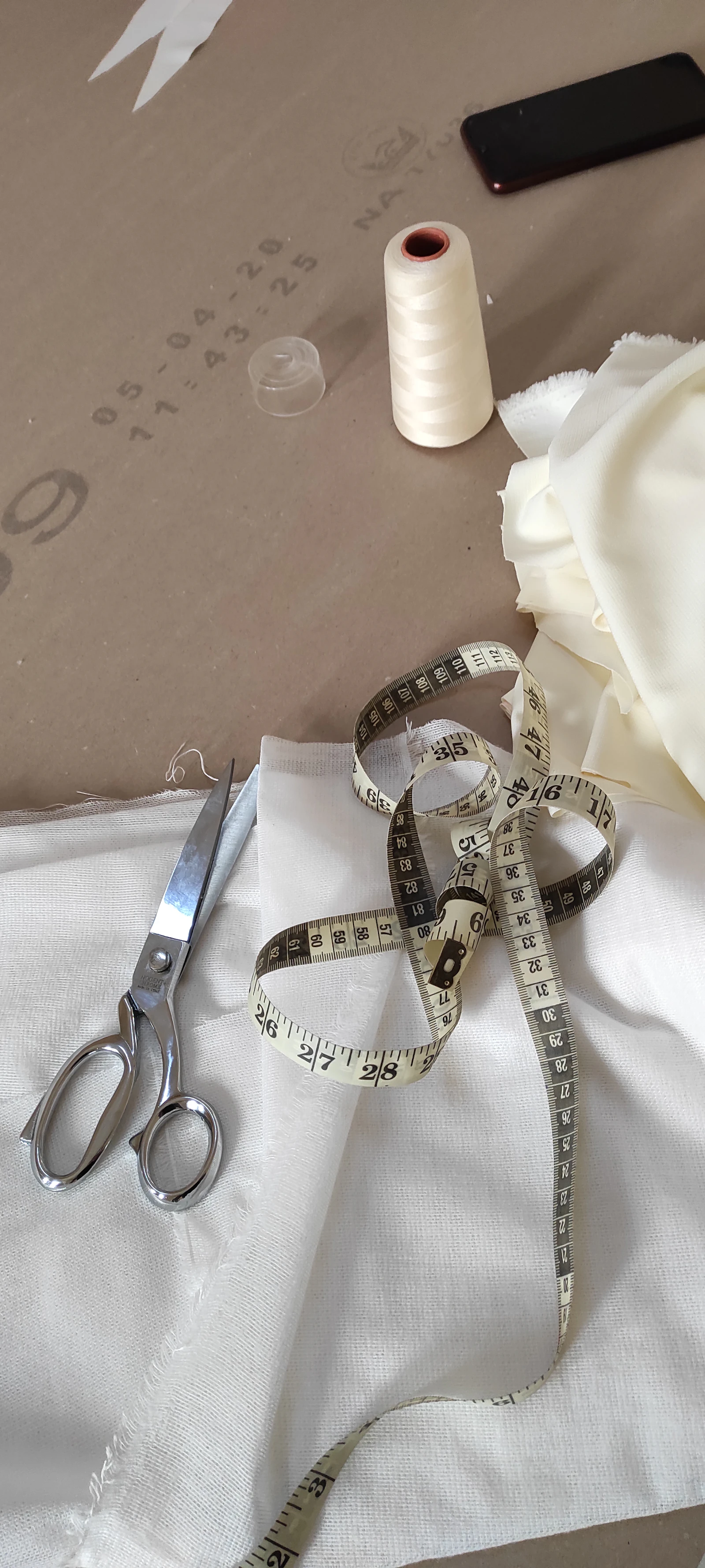Tailoring scissors and measuring tape on white fabric