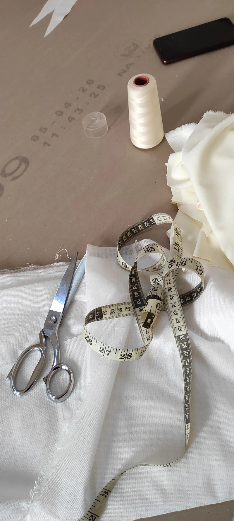 Tailoring scissors and measuring tape on white fabric
