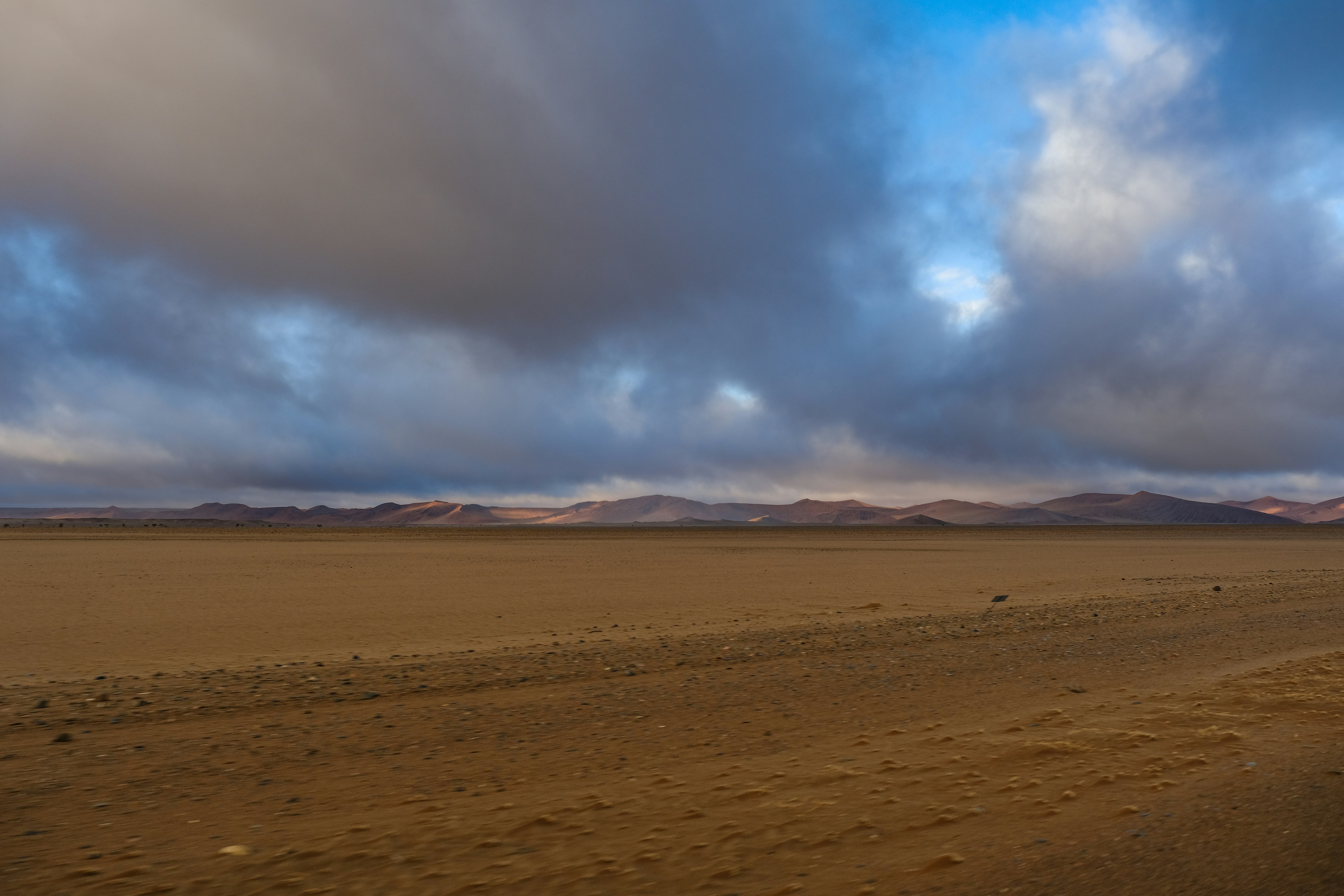 A vast desert landscape under a sky filled with heavy dark clouds