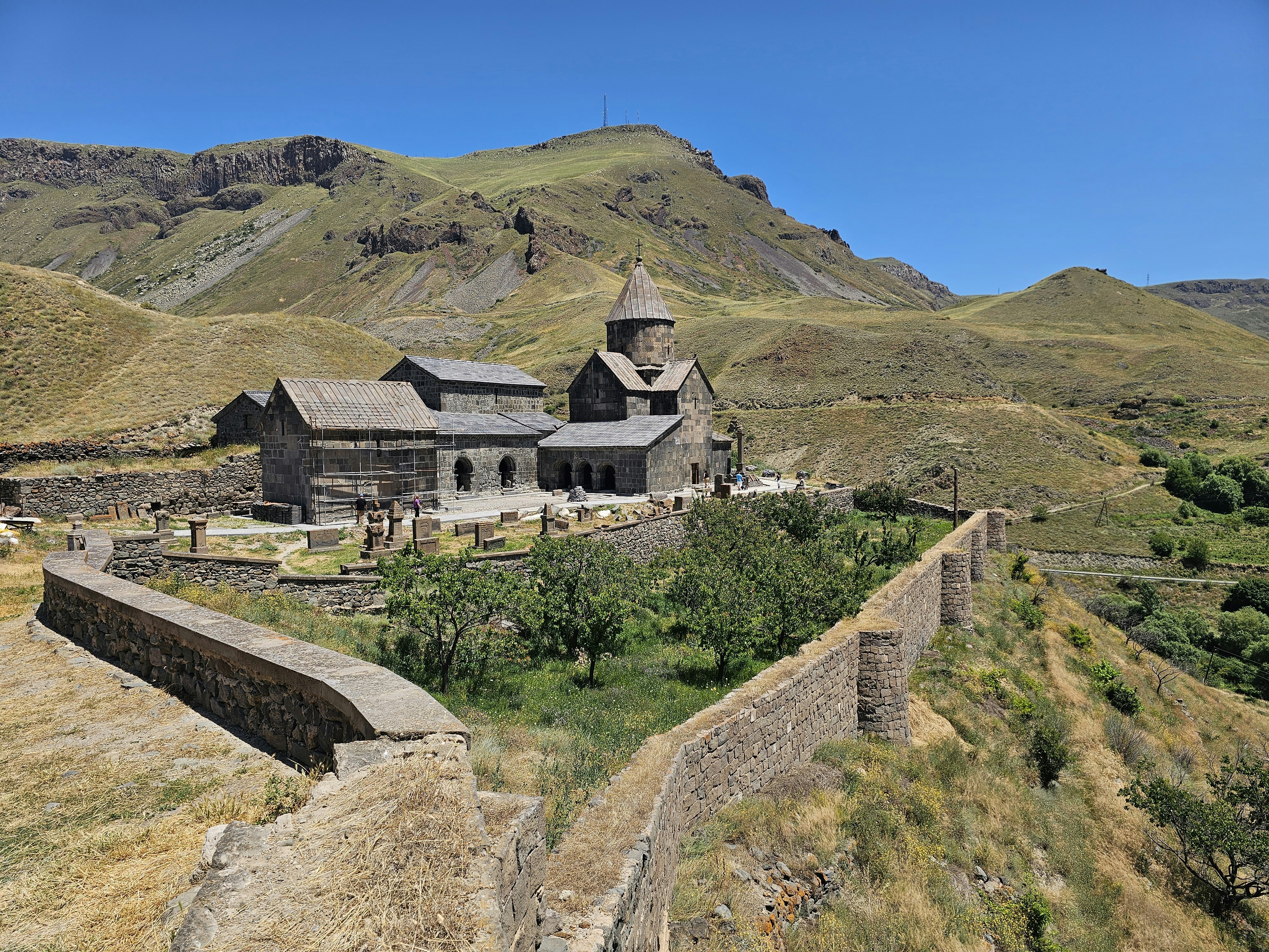 Stone monastery complex with a conical roof in a mountainous landscape