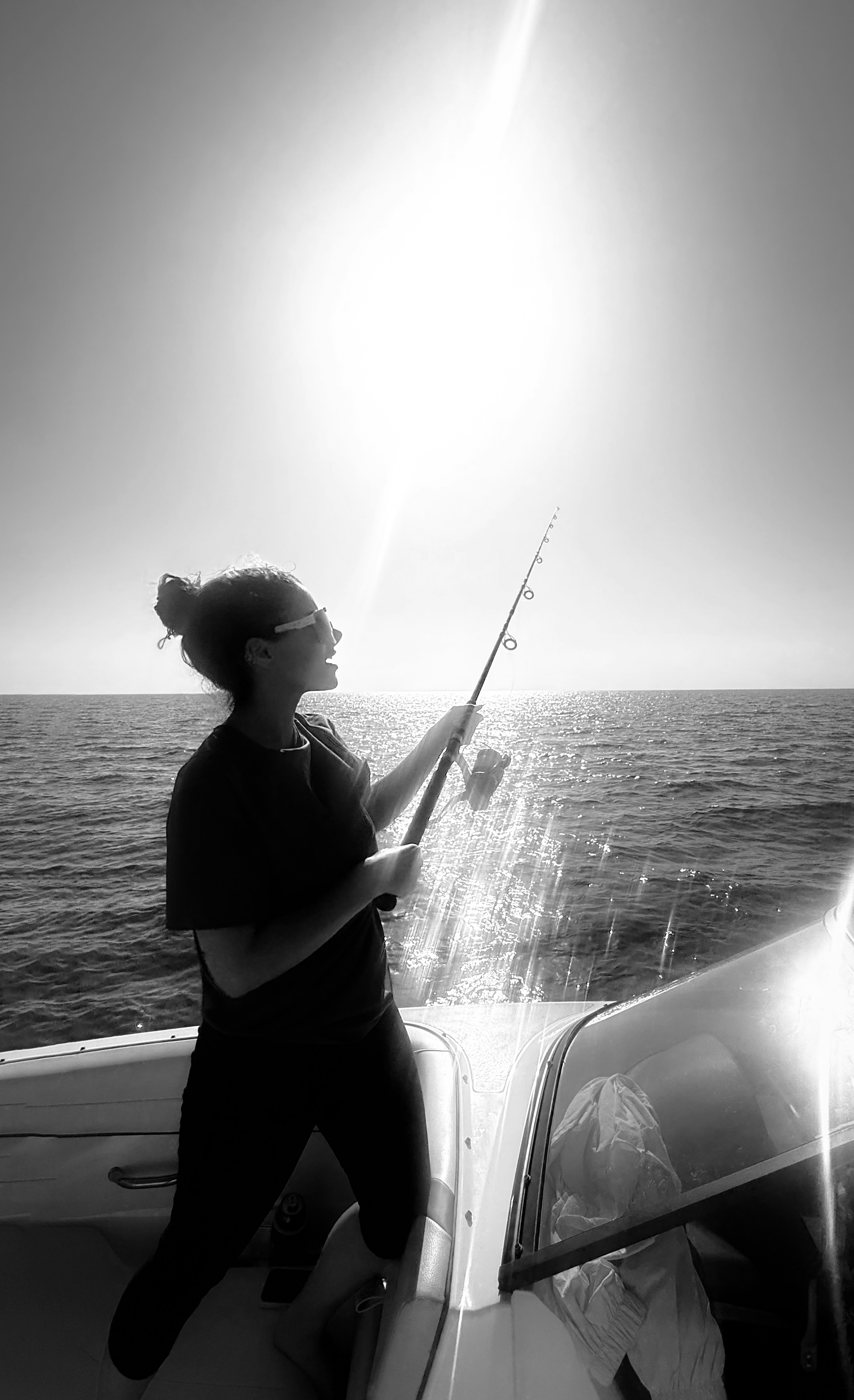 A woman fishing from a boat on the sea in Kish, Iran