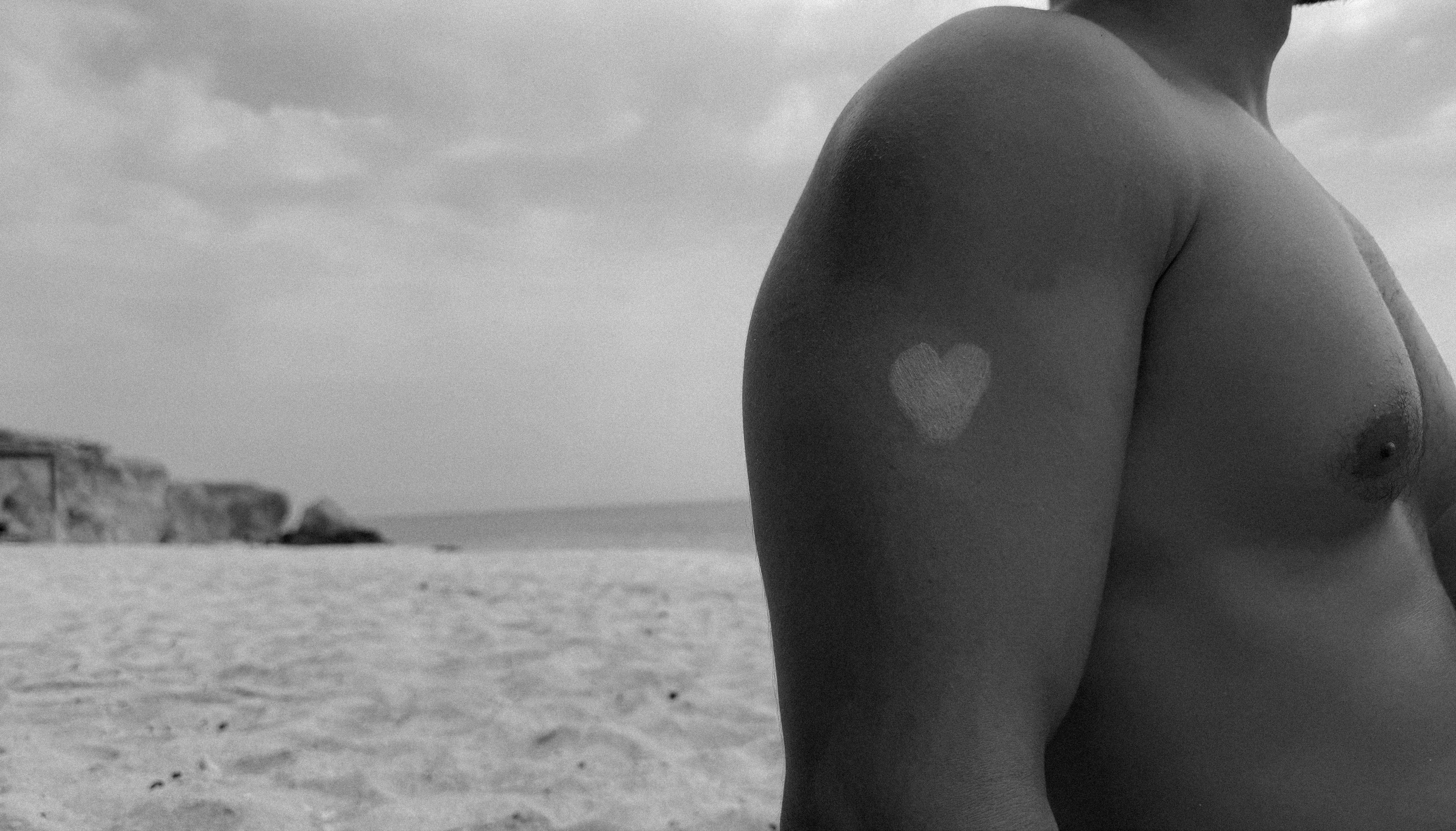 A person with a heart-shaped mark on their arm at a beach in Kish