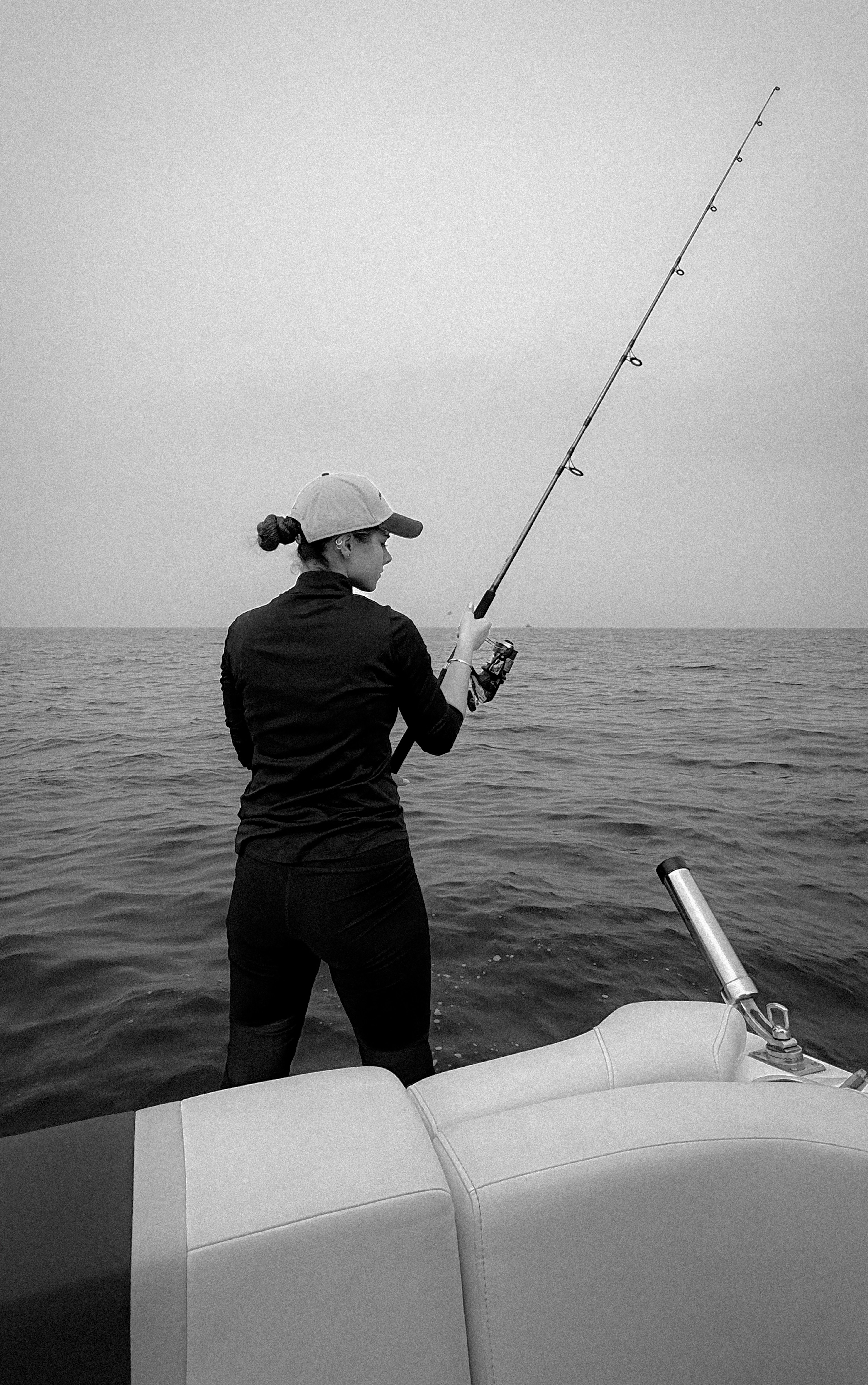 A woman in a cap fishing from a boat on the sea in Kish