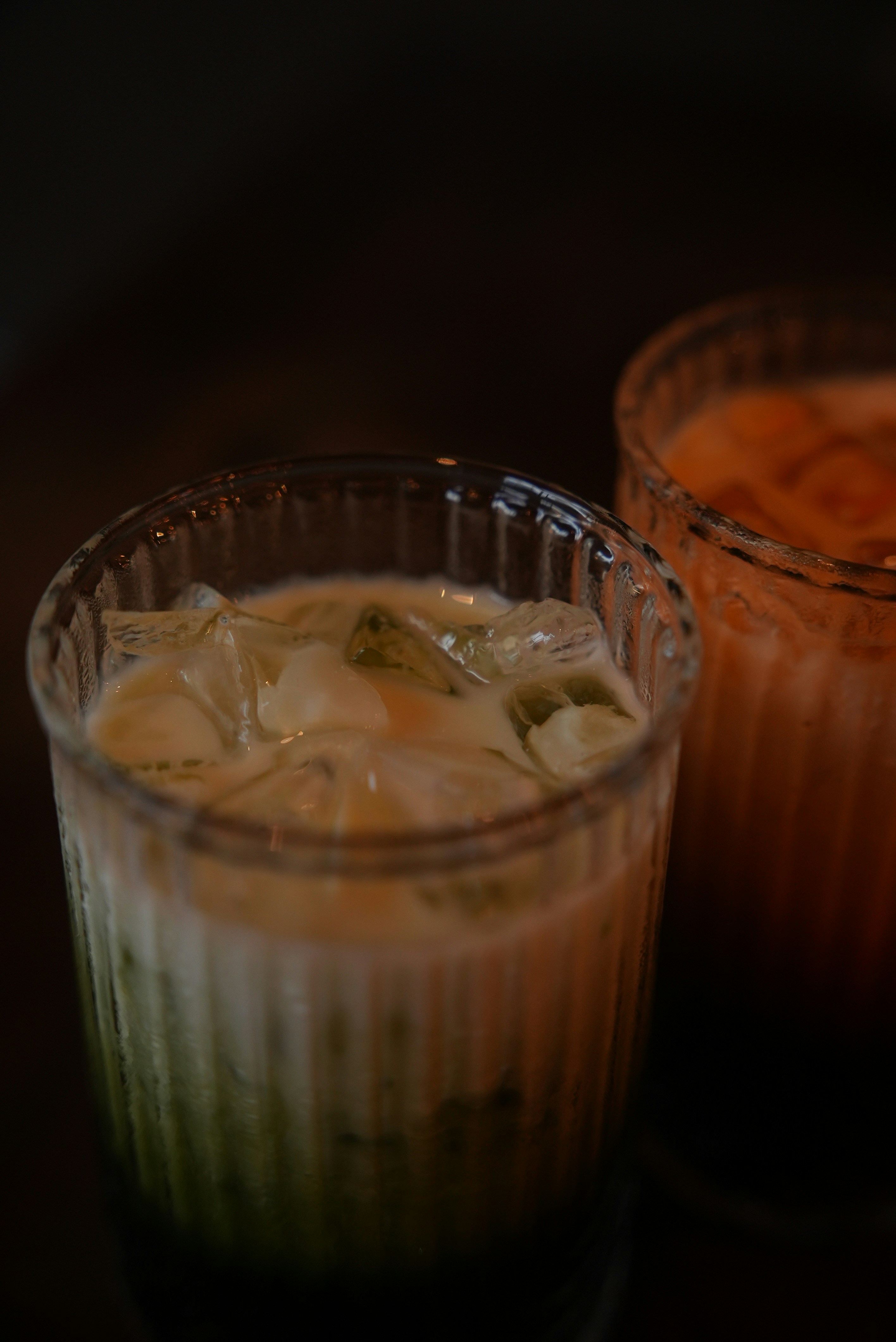 Two glasses of iced matcha latte with milk and ice cubes