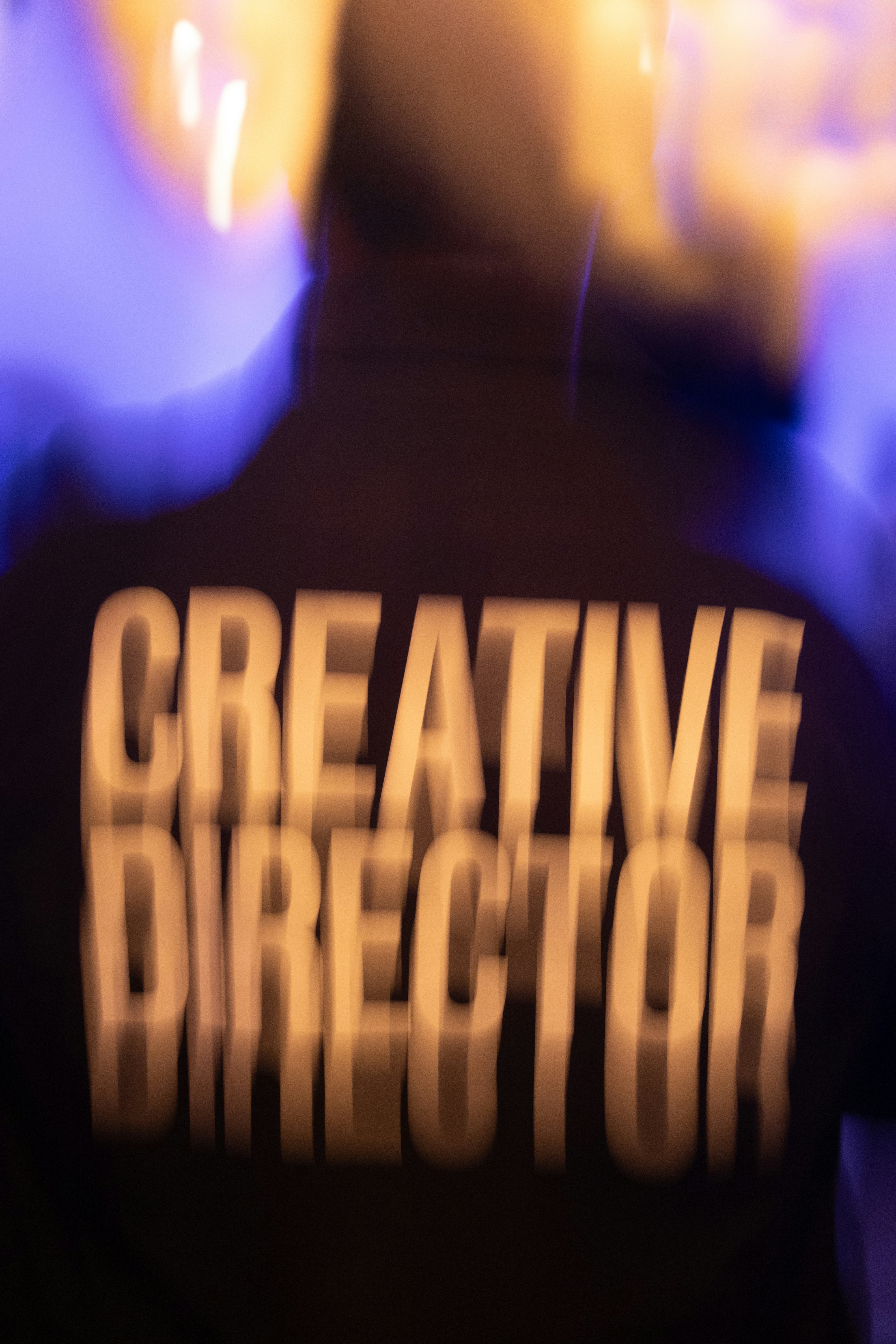 A person wearing a black shirt with the words CREATIVE DIRECTOR in white letters