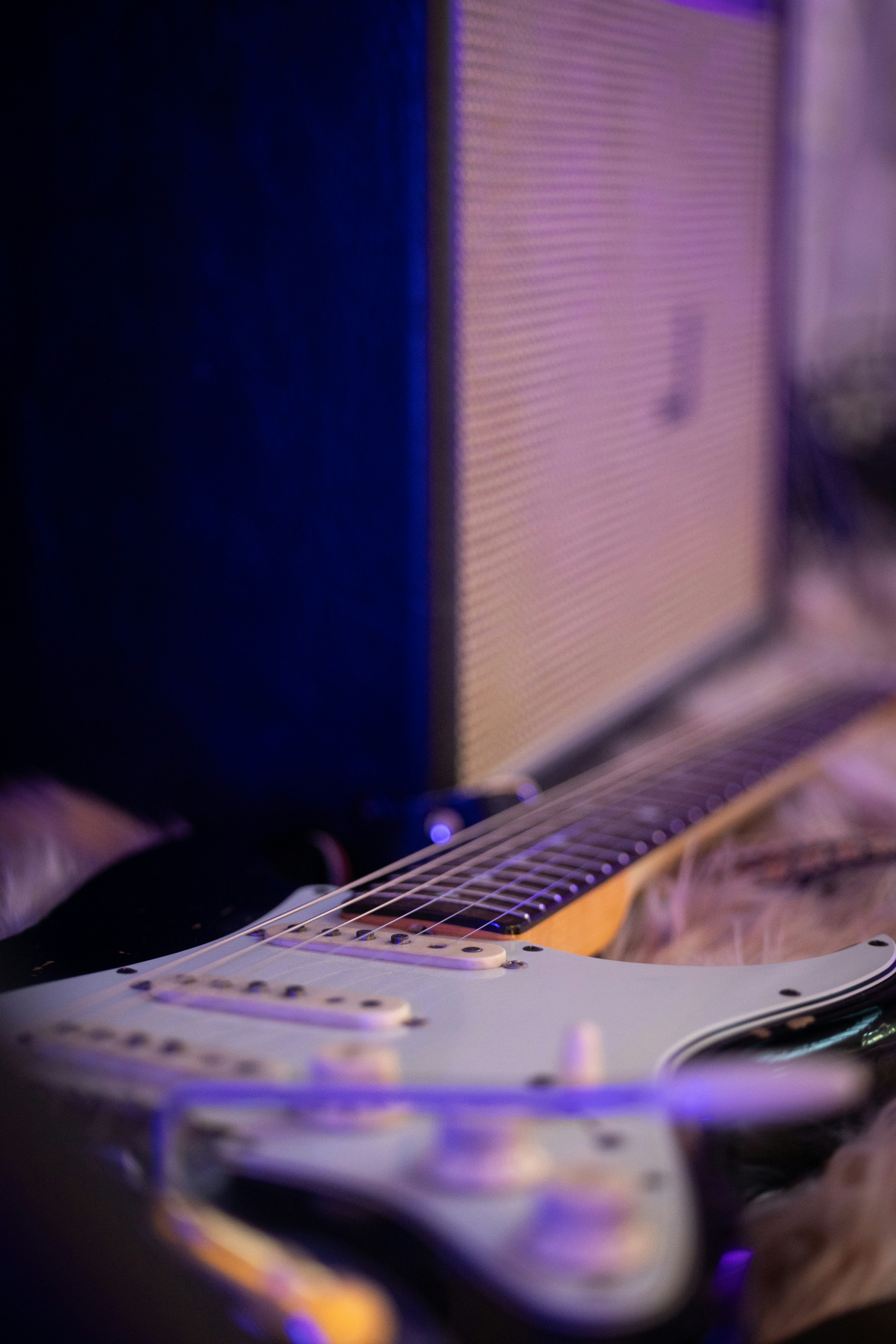 An electric guitar resting on a fuzzy surface in front of an amplifier