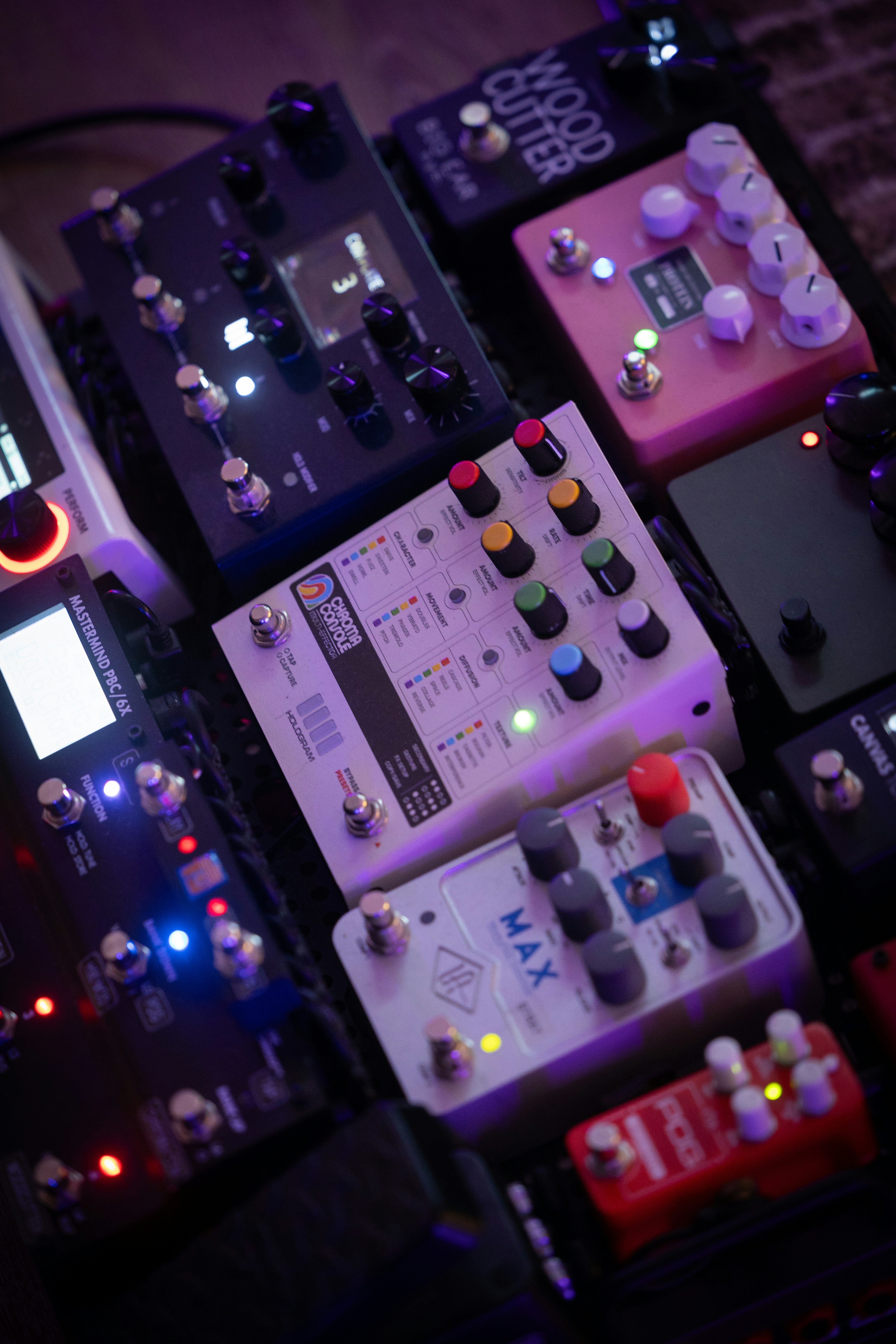 A collection of guitar effect pedals on a pedalboard with glowing indicator lights