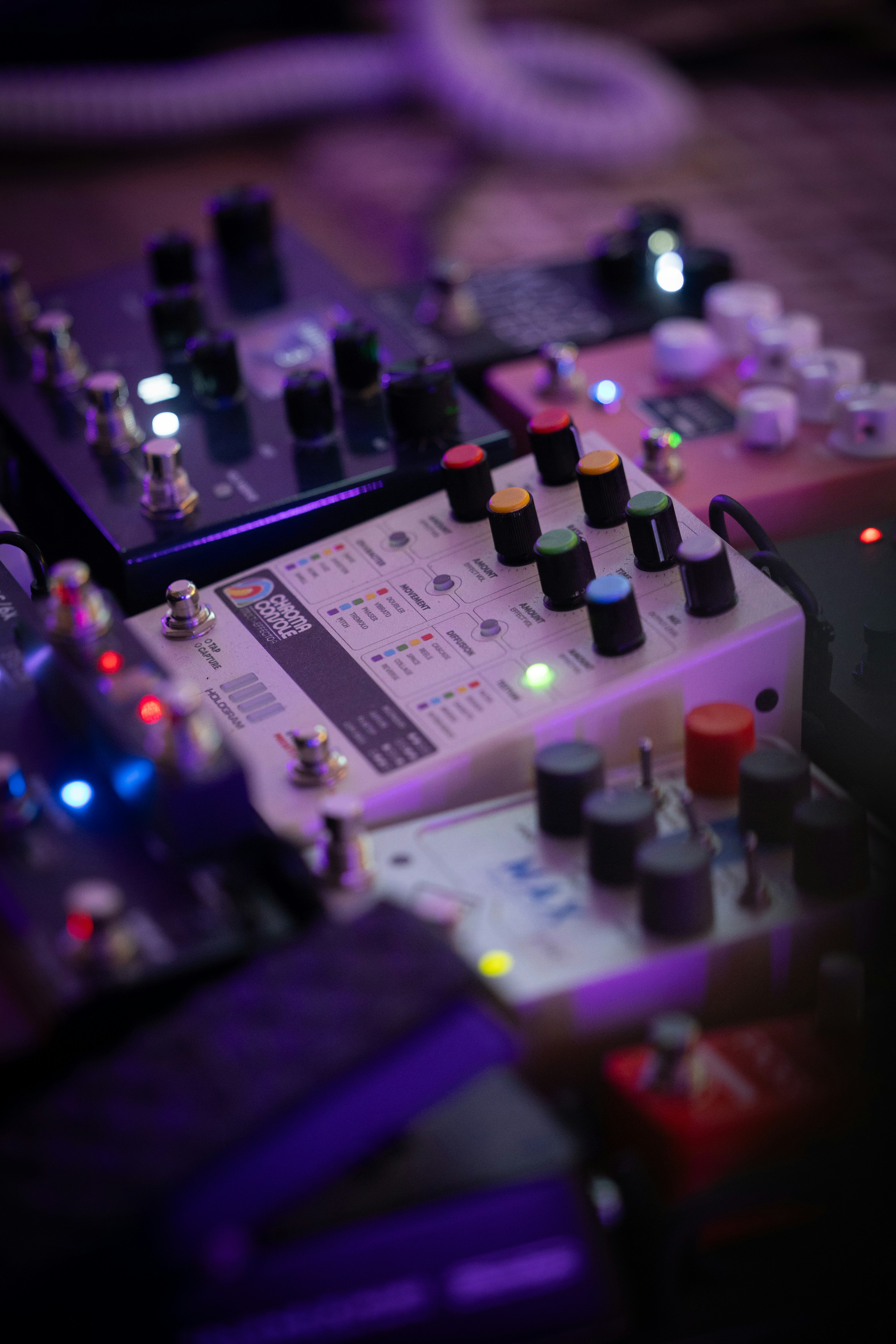 A collection of guitar effect pedals with glowing lights on a dark surface