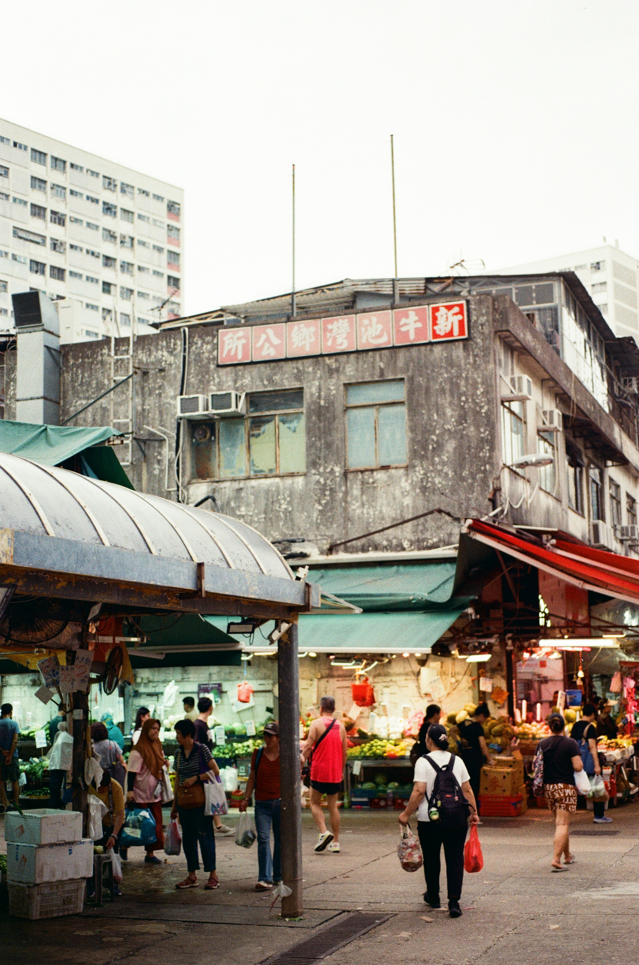 People walking through a busy outdoor market with produce stalls in Hong Kong