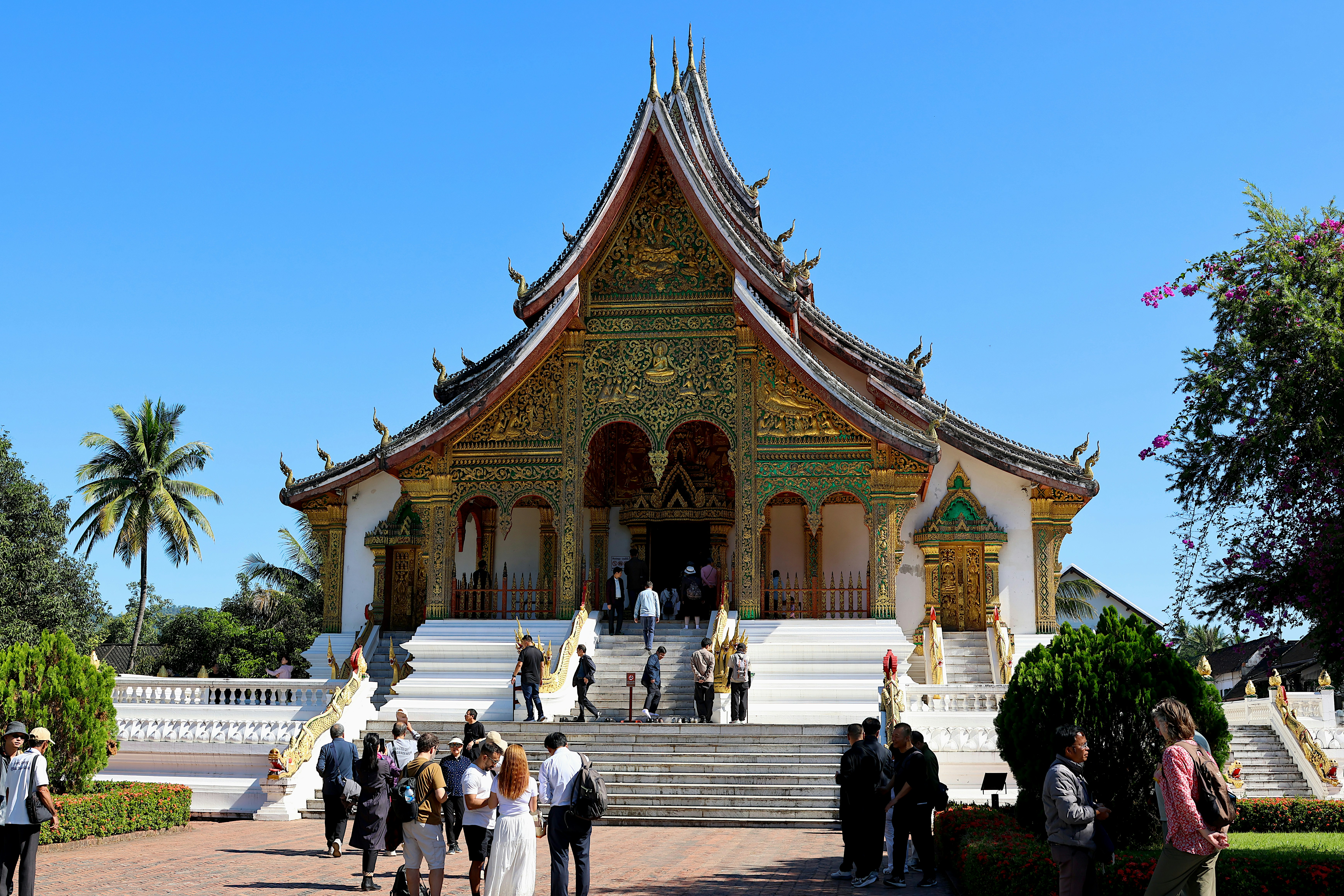 People visiting the ornate Wat Xieng Thong temple in Luang Prabang, Laos