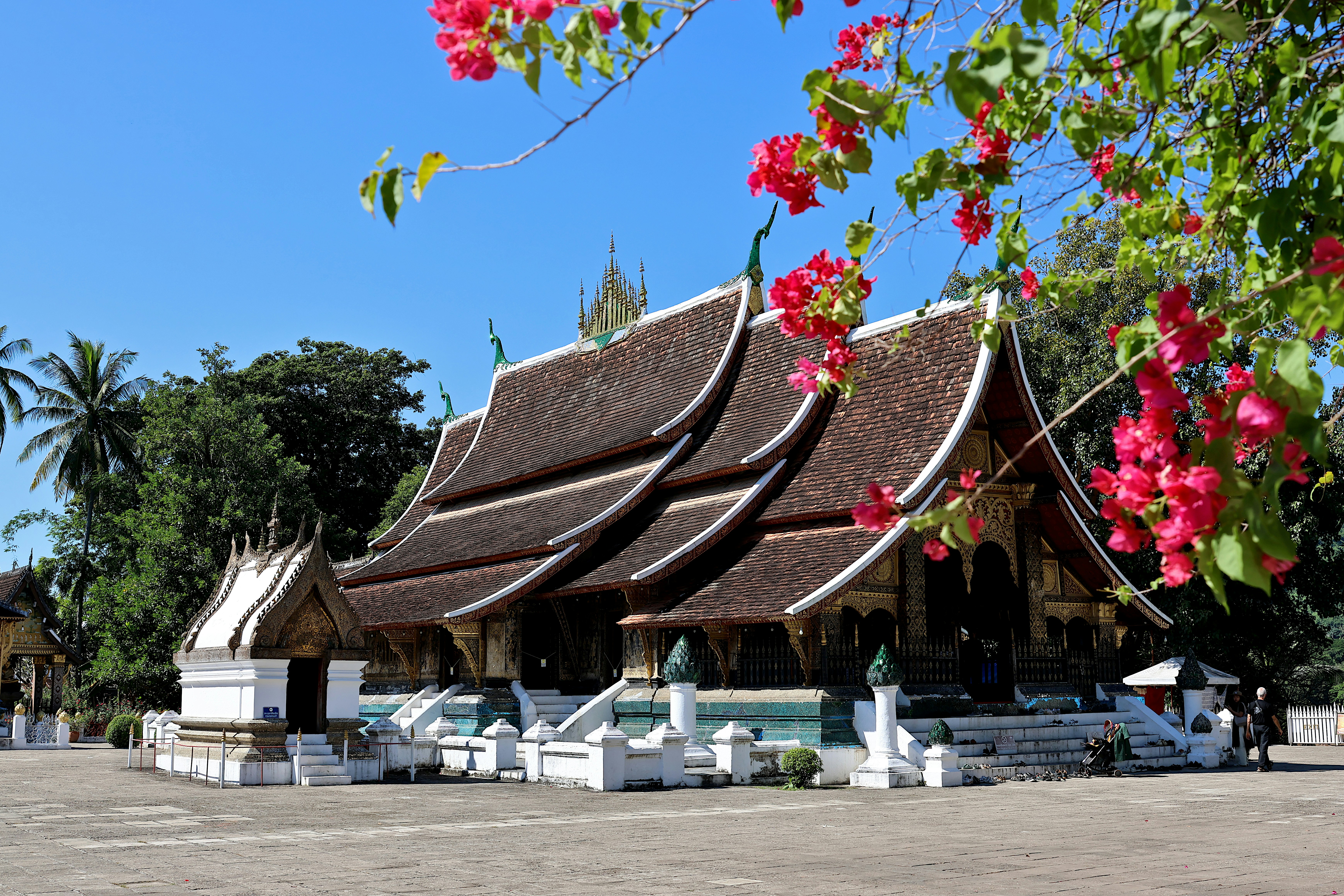 Wat Xieng Thong temple with tiered roof and bougainvillea flowers in Luang Prabang