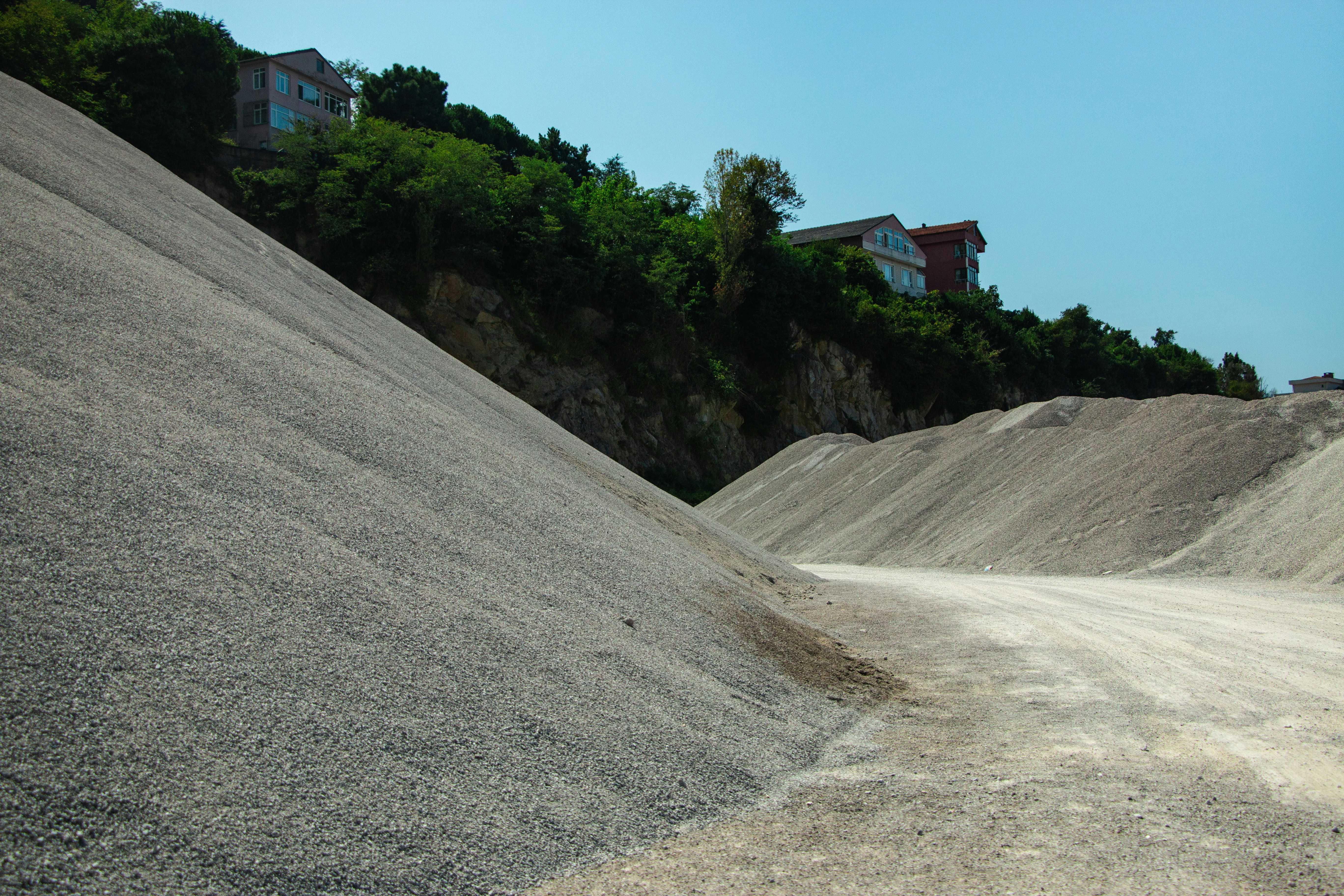 Montes de brita e areia ao pé de um morro verde