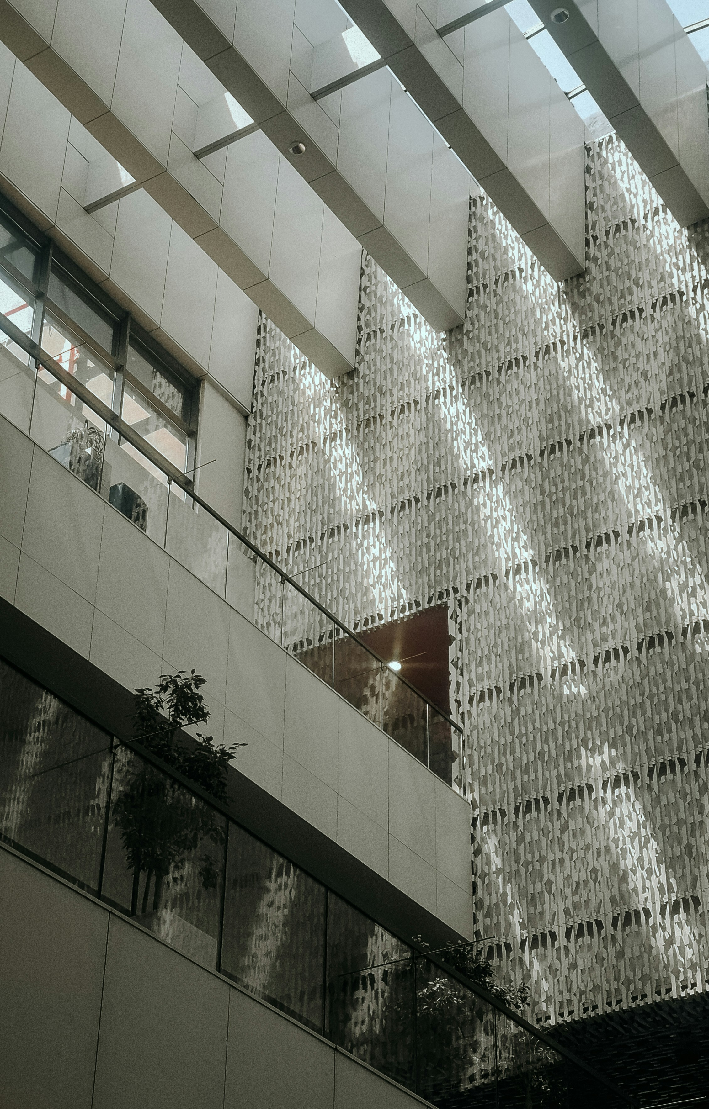 Sunlight casting long shadows across a textured white wall in a modern atrium