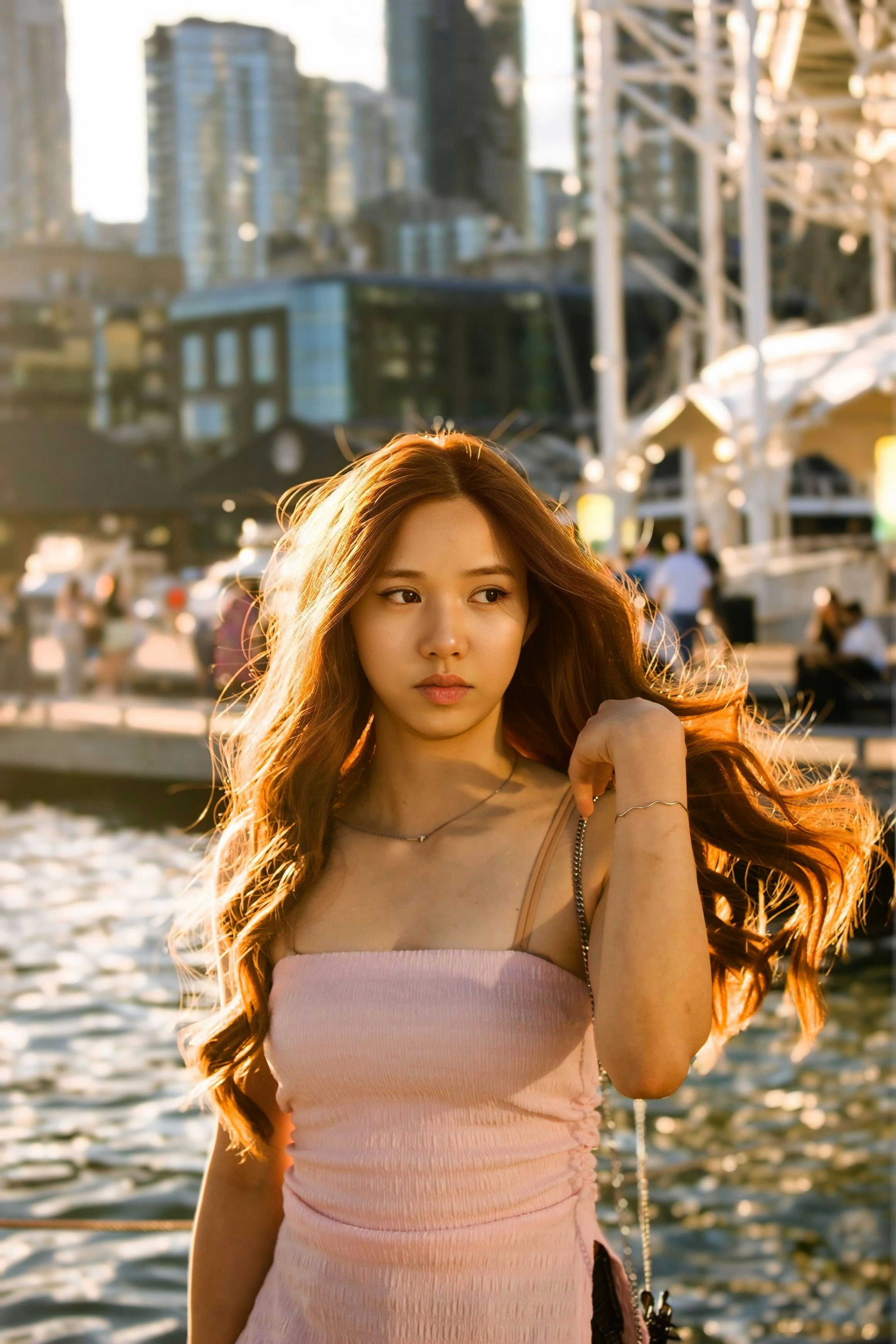 A woman in a pink top standing by the water at golden hour