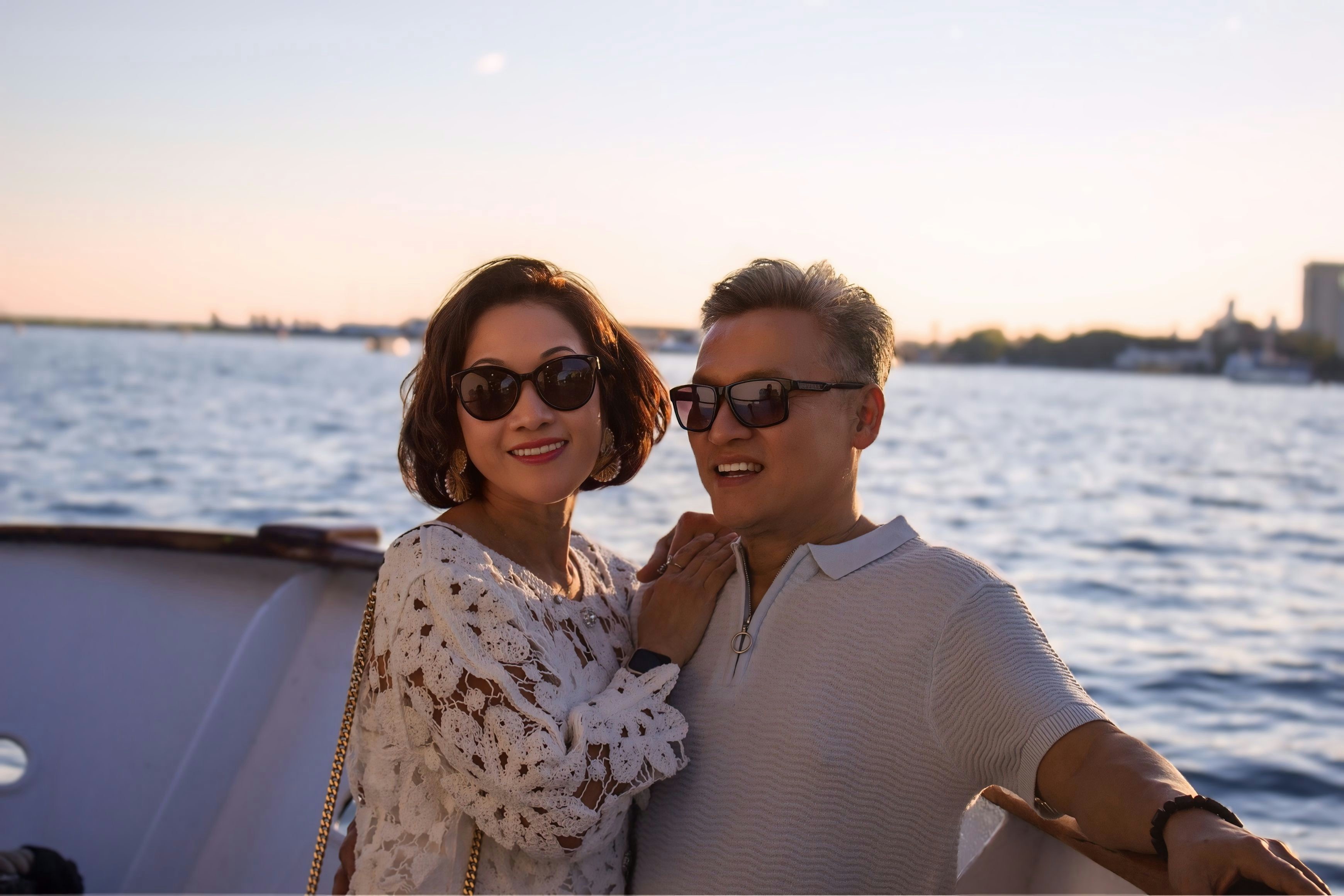 A woman and a man in sunglasses on a boat at golden hour