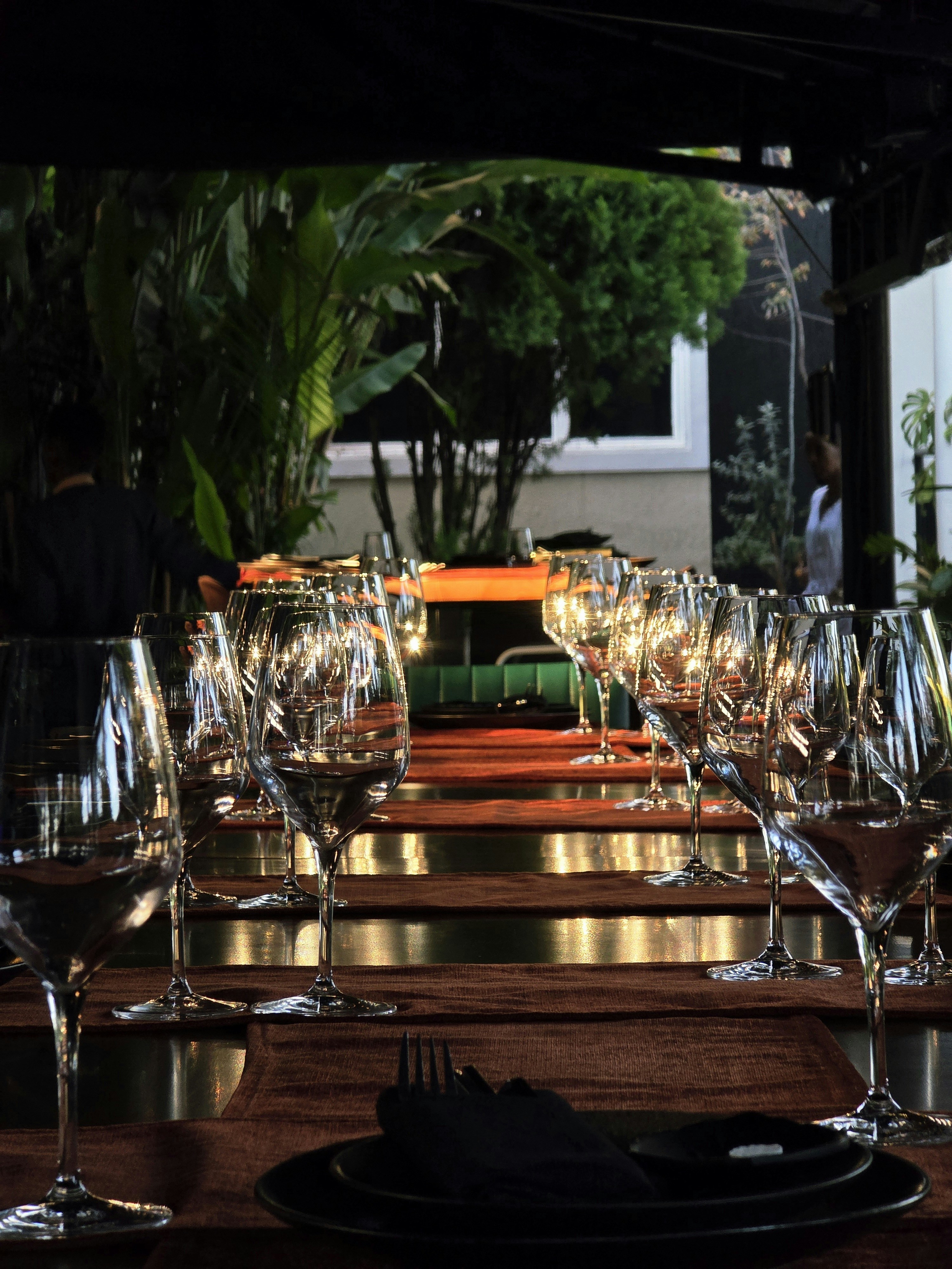 Empty wine glasses arranged in rows on a long table in a restaurant