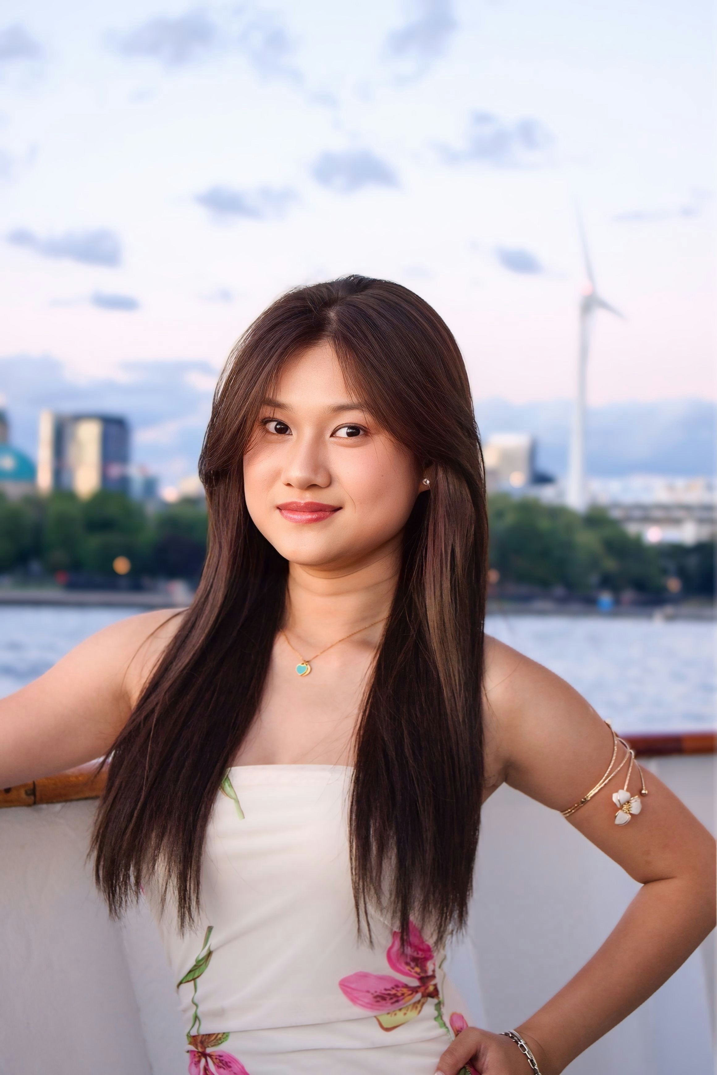 A woman with long brown hair wearing a floral dress on a boat deck