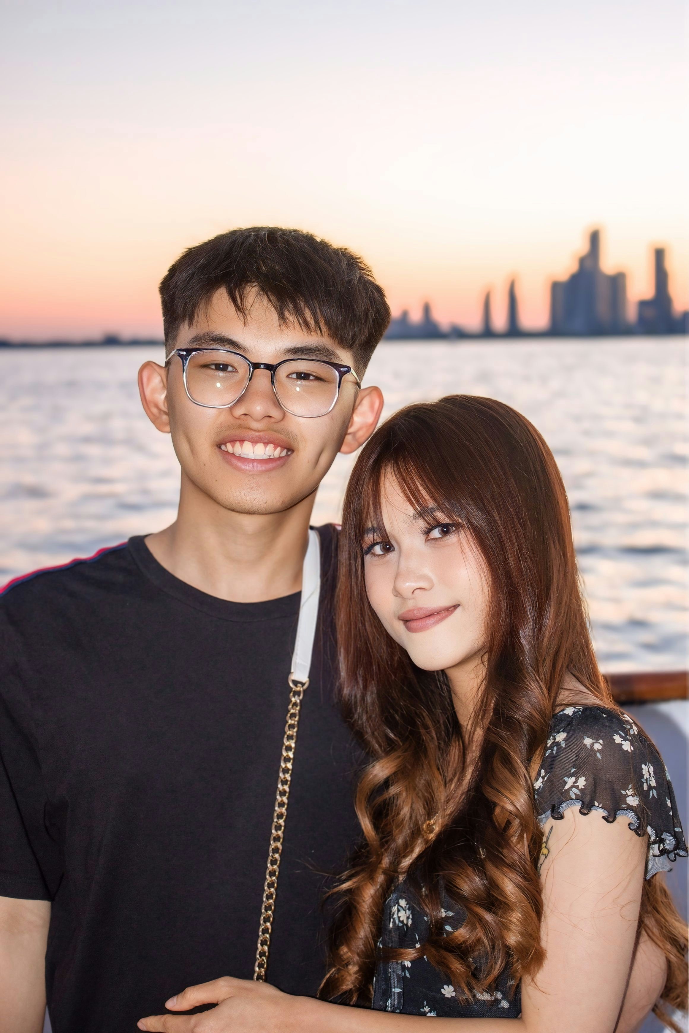 A young man and woman posing together on a boat at golden hour