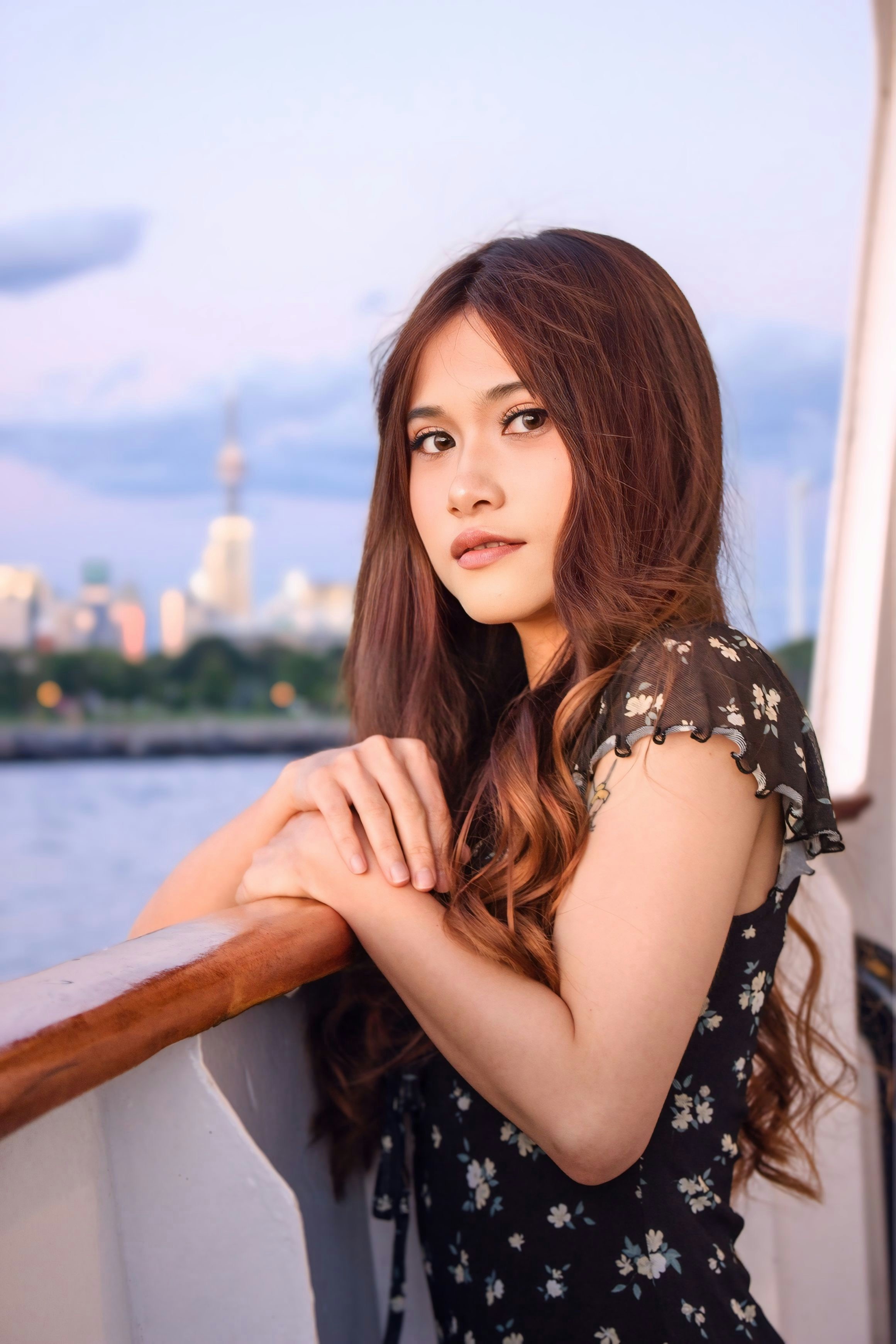 A woman with long brown hair leaning on a railing on a boat