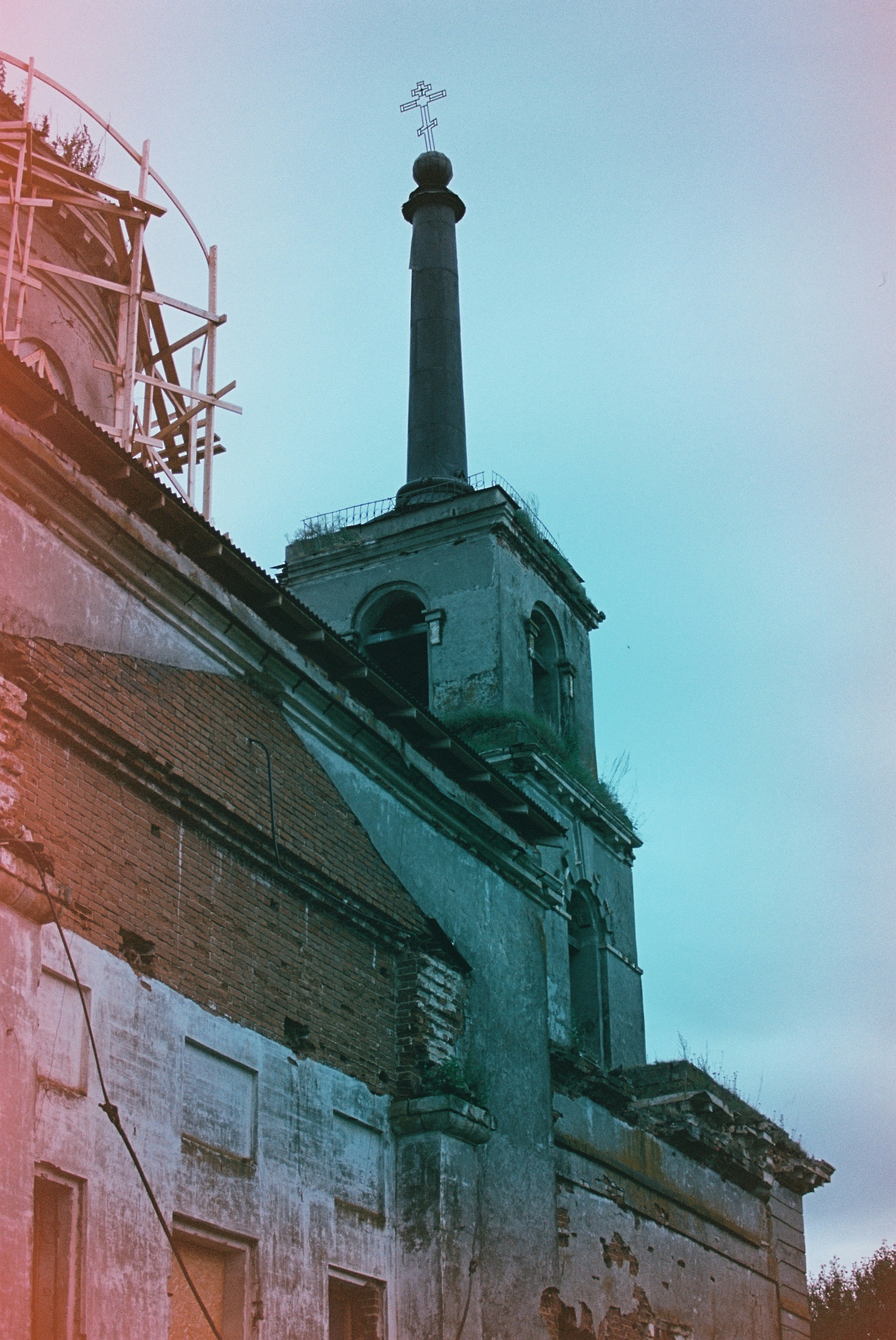 Eine alte Backsteinkirche mit hohem Turm und einem Kreuz vor dem Himmel