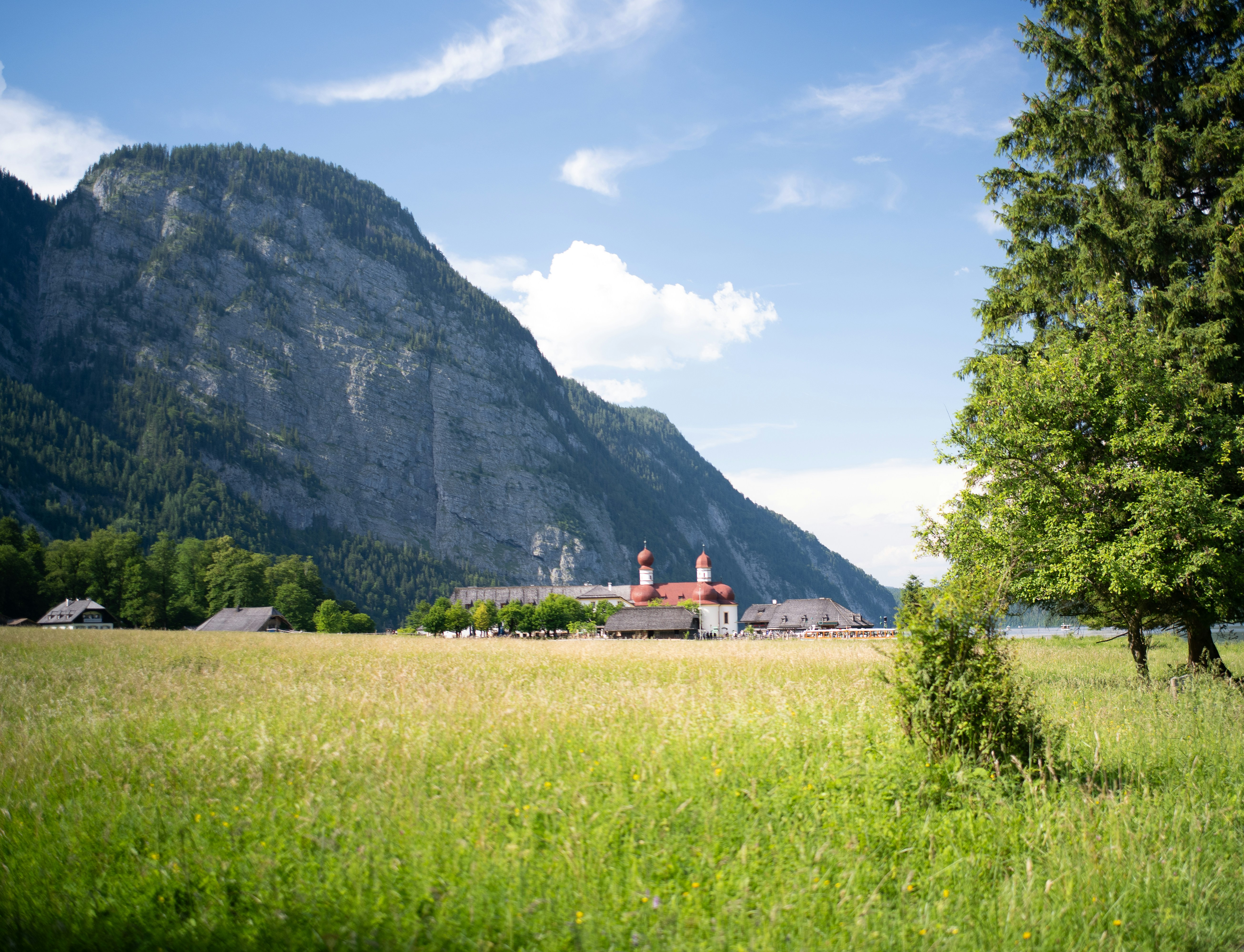 St. Bartholomä church with red domes in a green valley below steep mountains