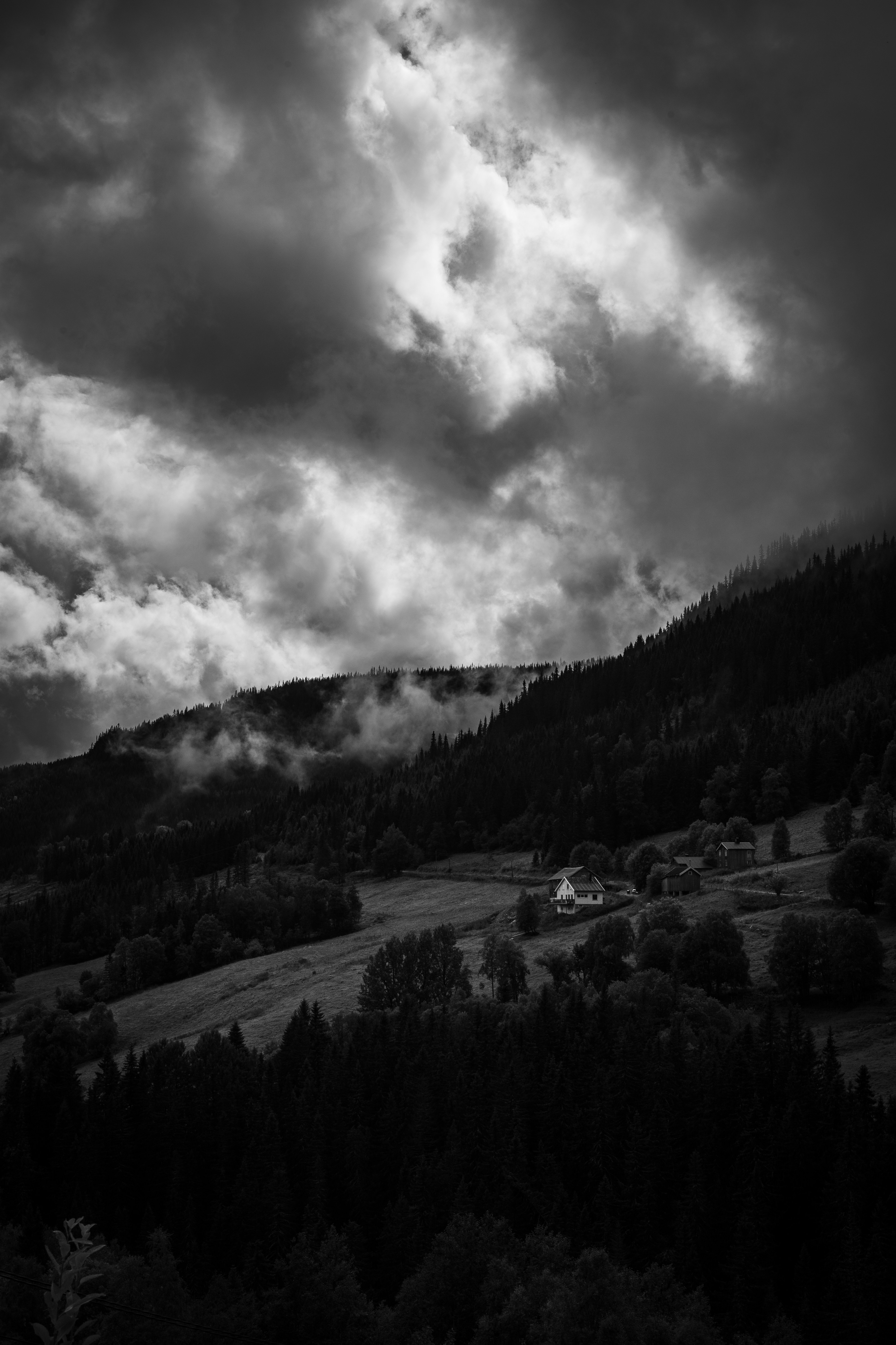 Small houses on a grassy hillside beneath a dark, cloudy sky
