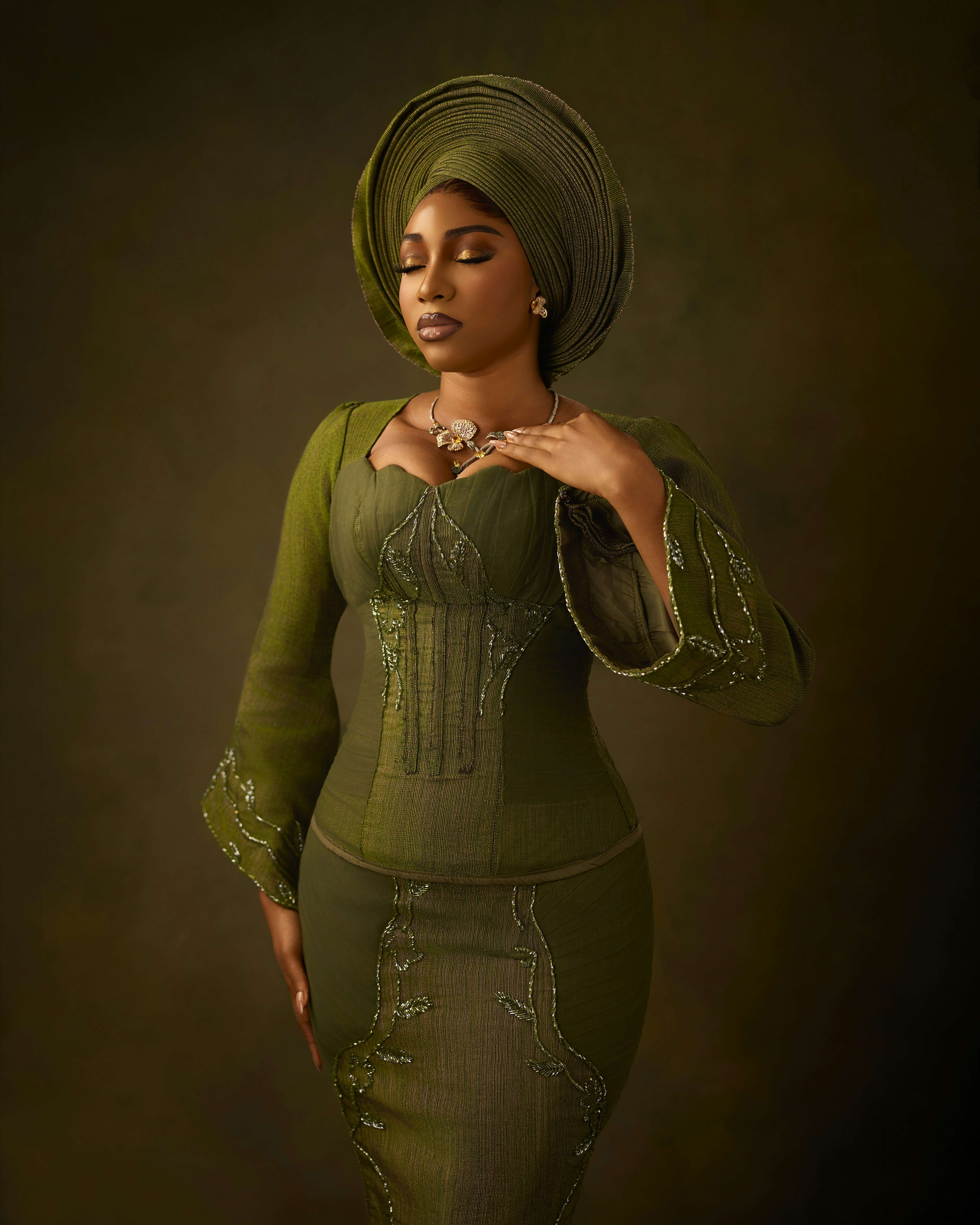 A woman in a green dress and matching headwrap with eyes closed