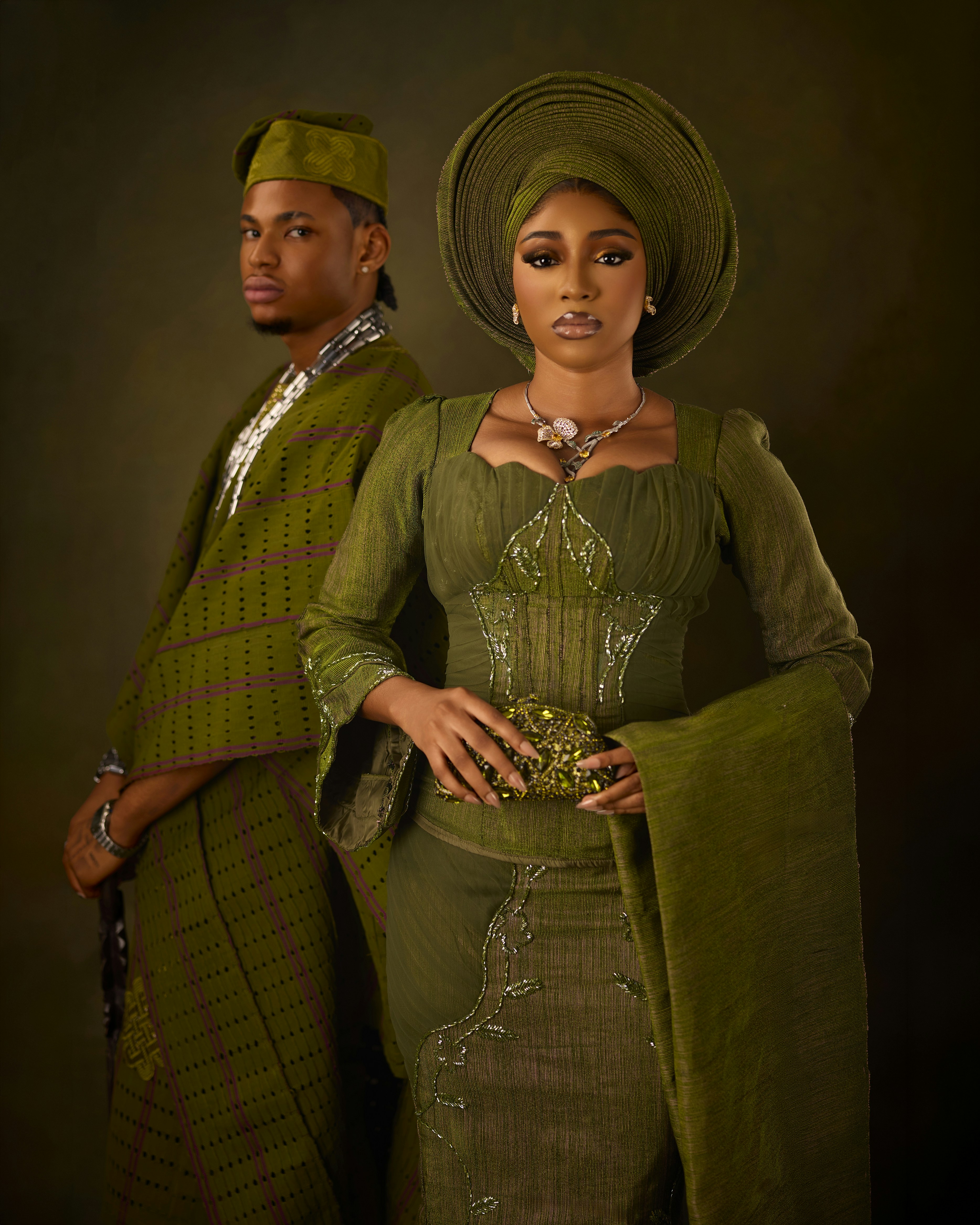 A man and a woman in traditional olive green Nigerian attire against a dark background