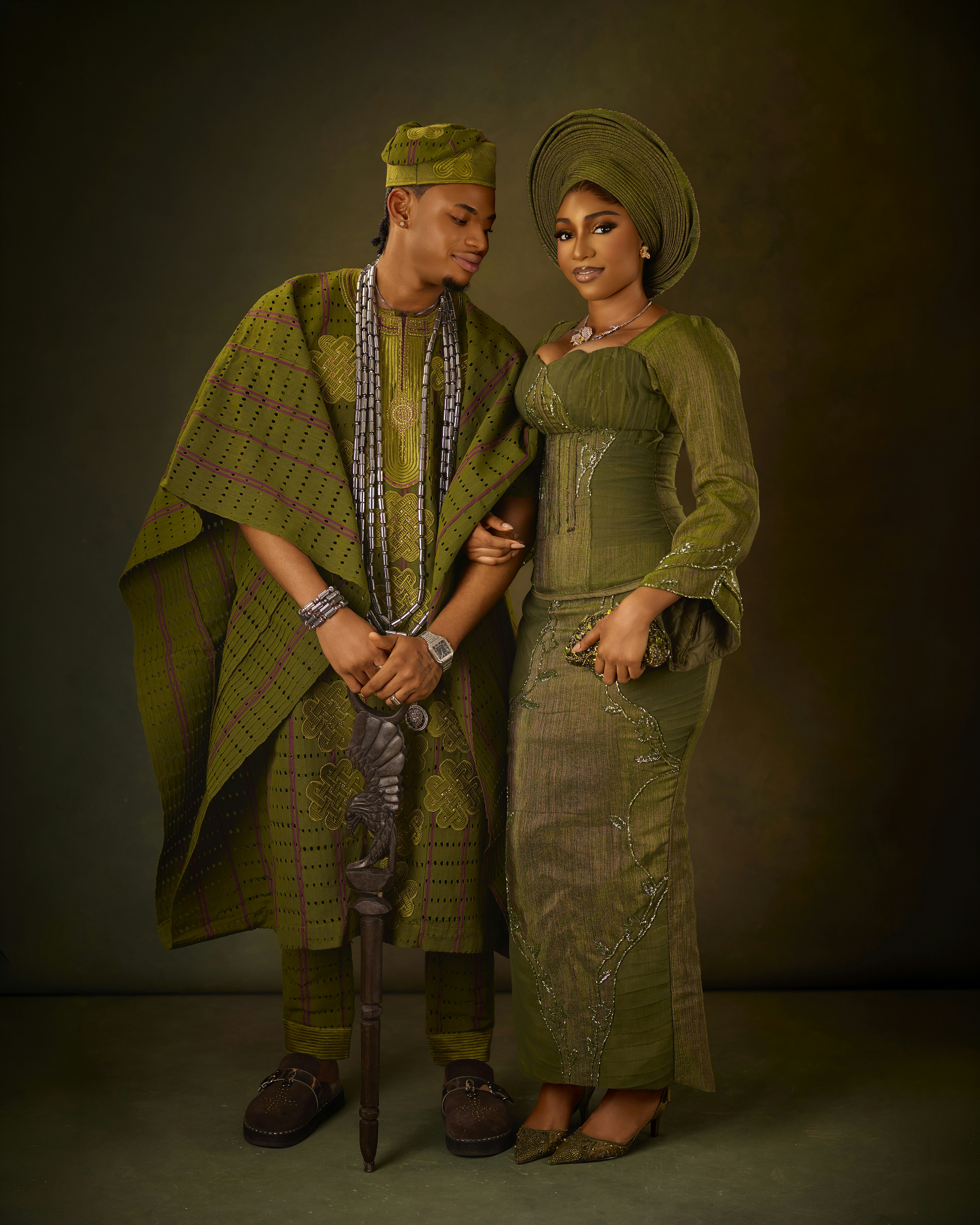 A man and a woman in traditional olive green Nigerian wedding attire