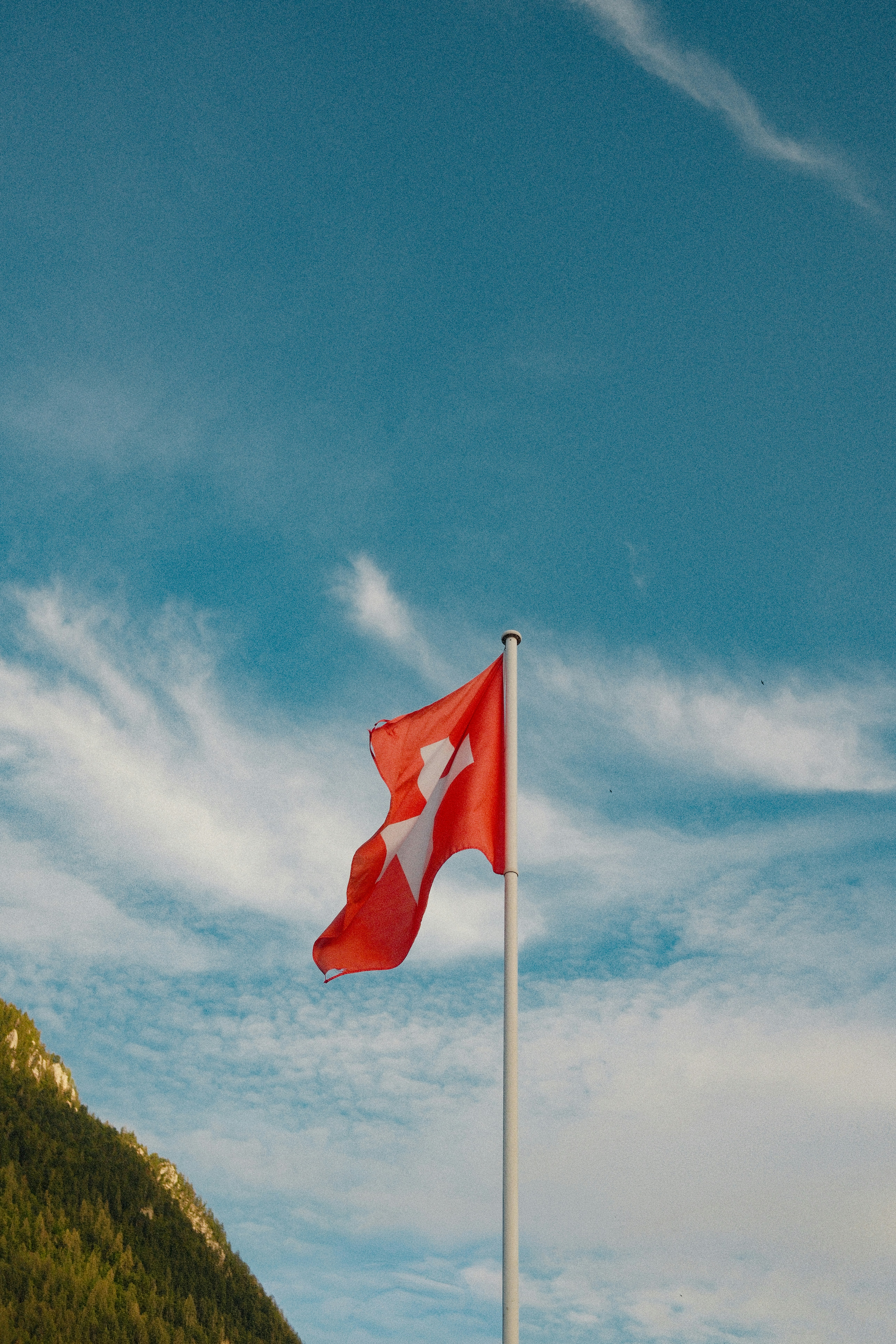 Le drapeau suisse flottant sur un mât contre un ciel bleu en Suisse