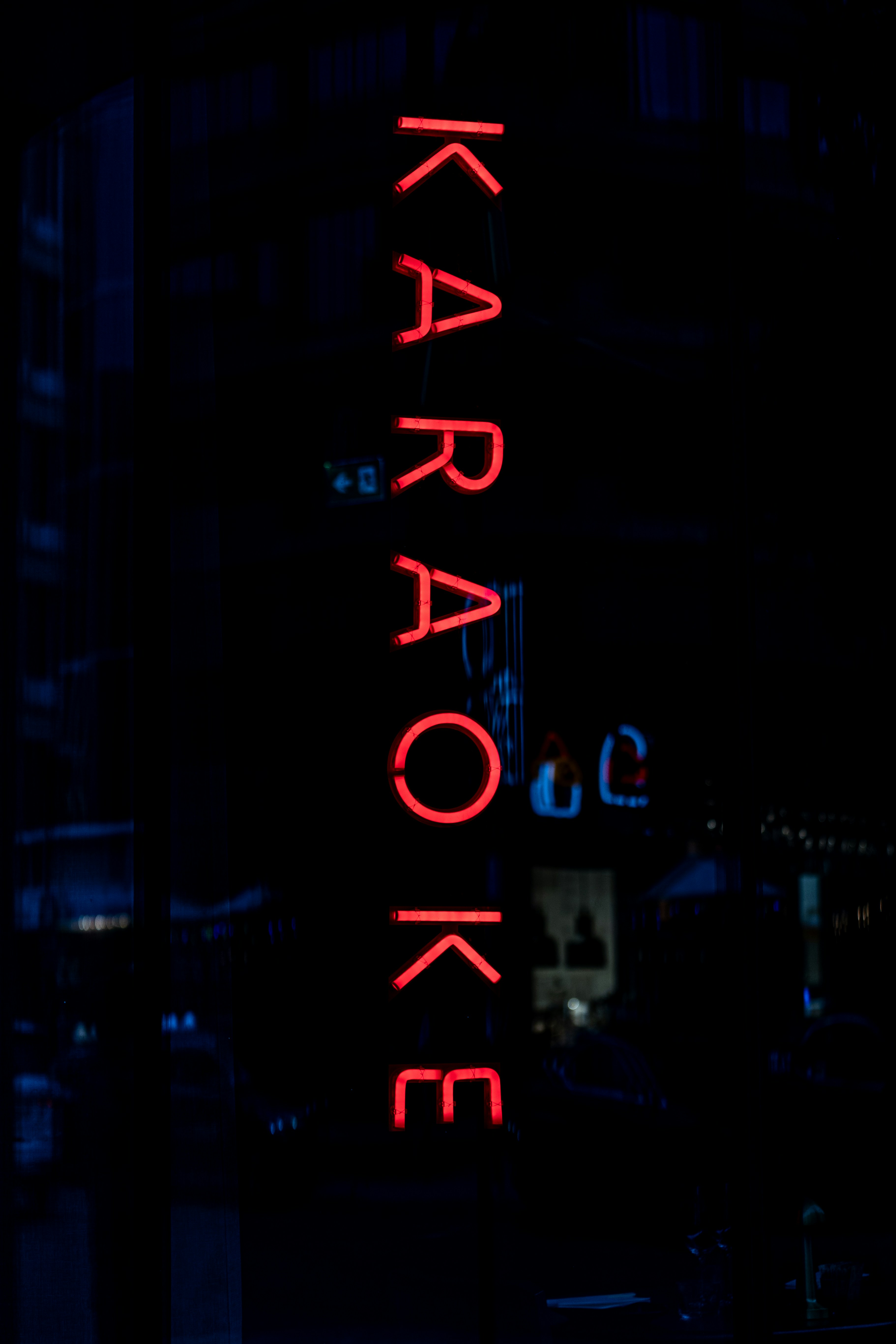 A vertical red neon sign reading "KARAOKE" against a dark night background