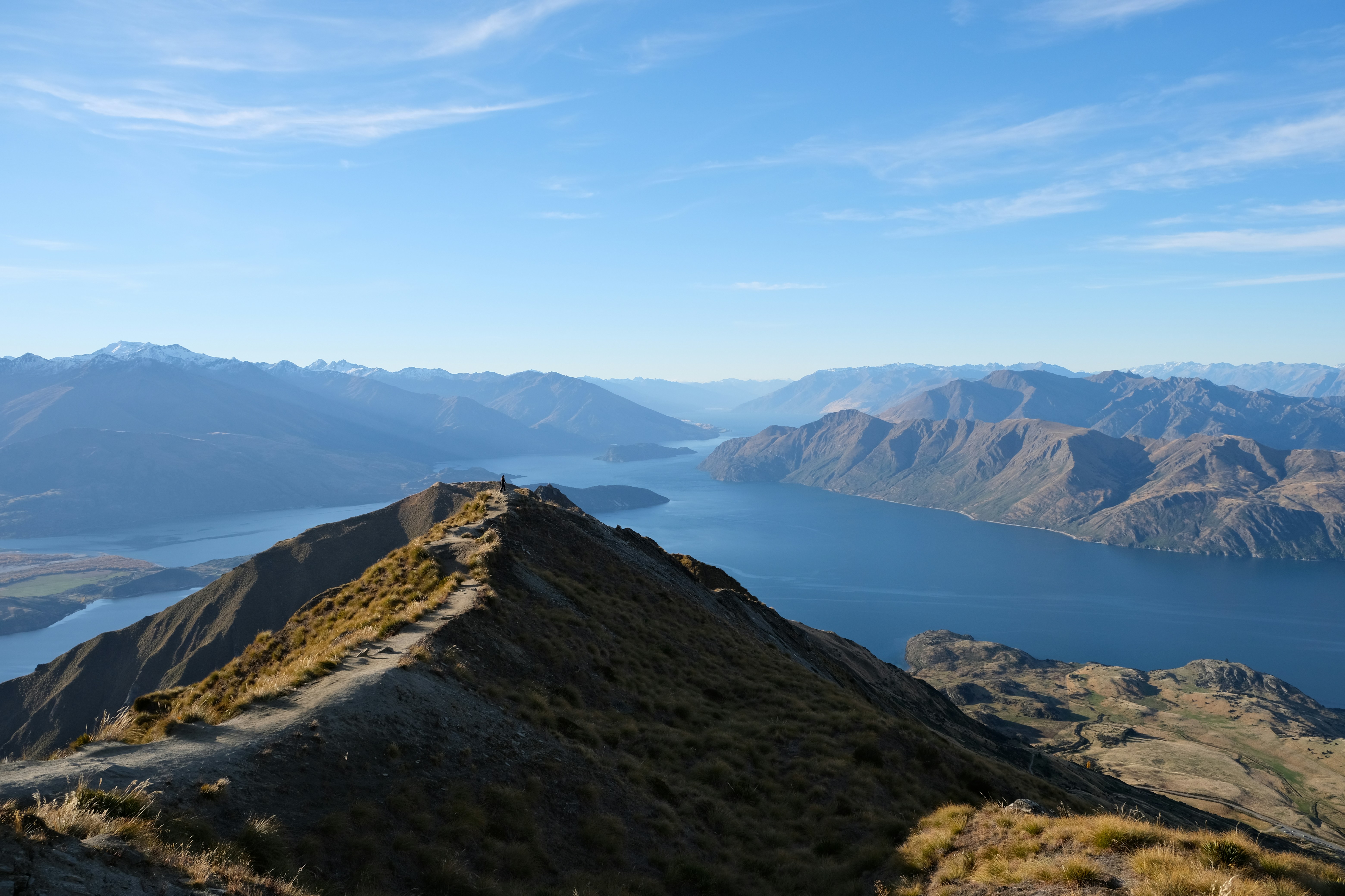 Un sentiero stretto lungo una cresta montuosa che domina un grande lago blu