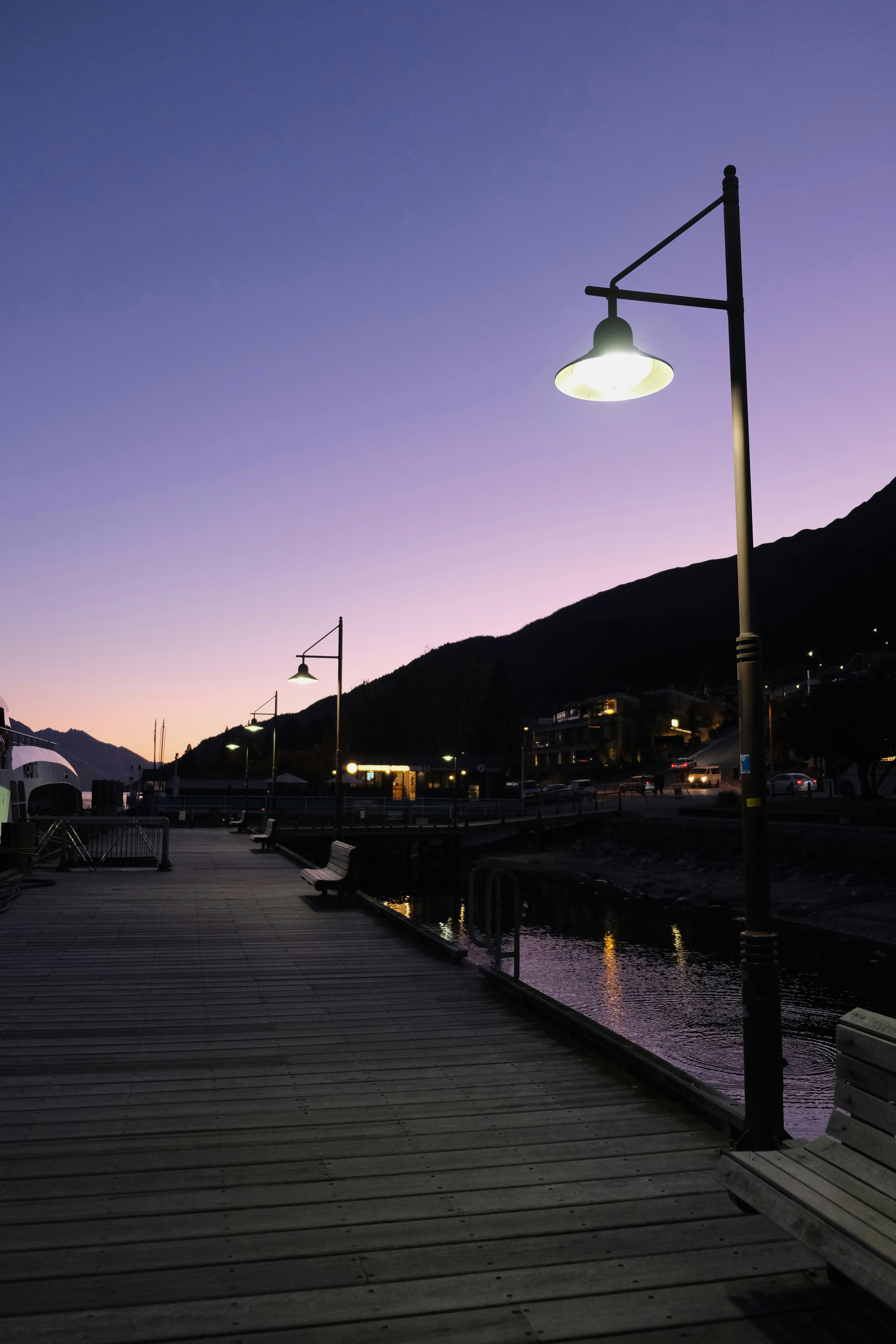 Un molo di legno con lampioni luminosi lungo un lungomare buio di notte