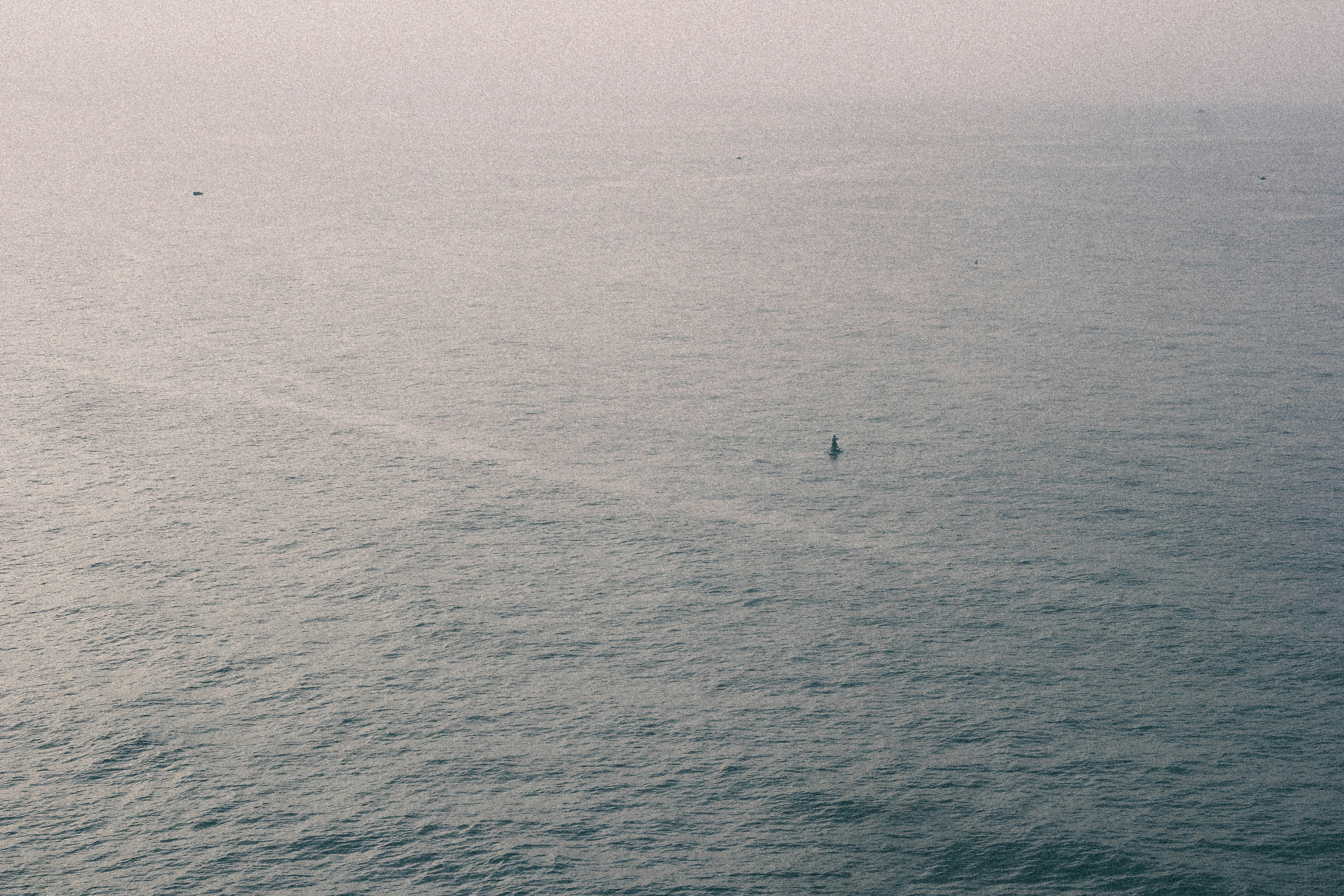 A lone person on a paddleboard in the middle of a vast misty ocean