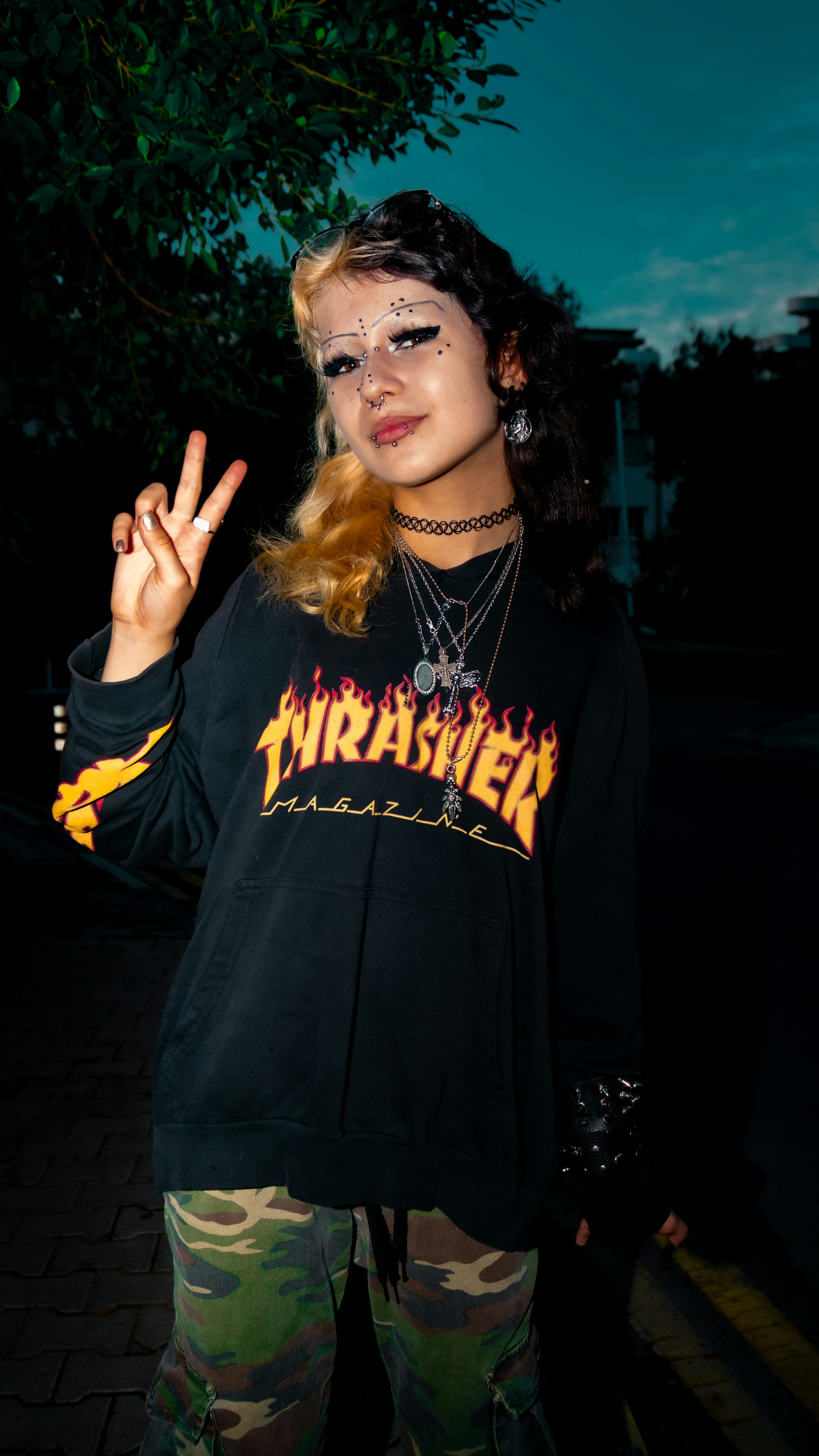 A person with two-toned hair making a peace sign in a black hoodie