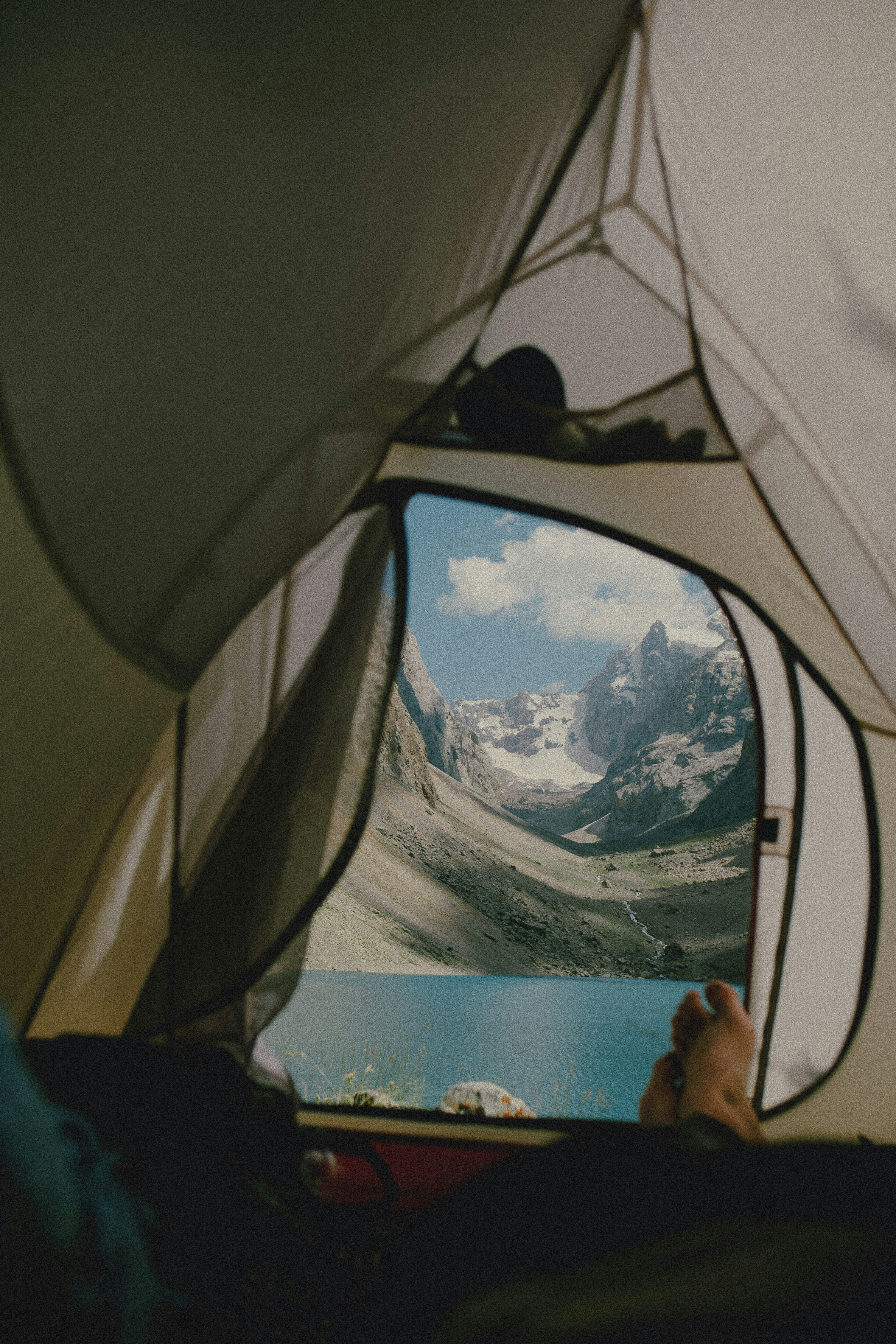 A view from inside a tent looking out at a blue lake and mountains