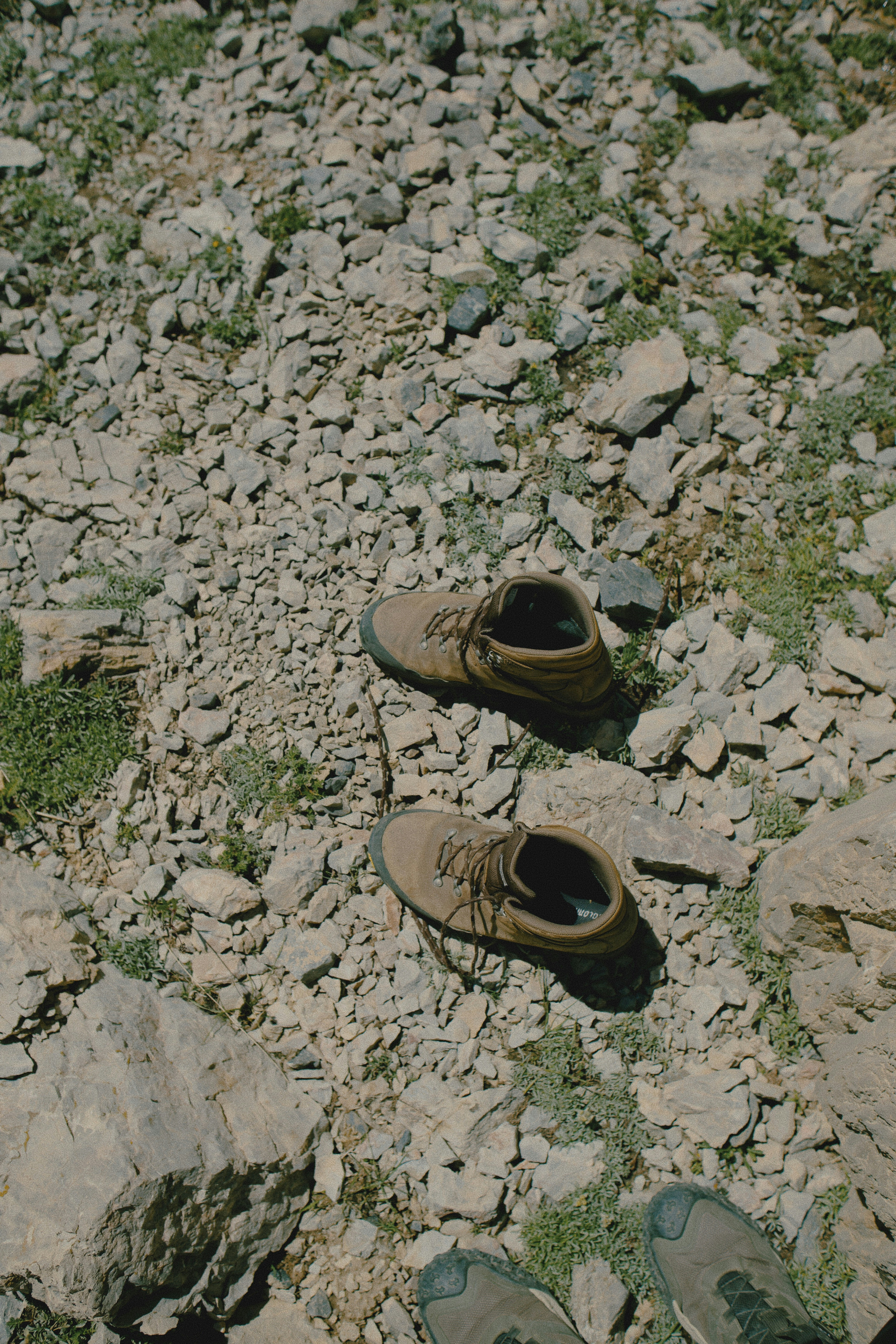 A pair of brown leather hiking boots on a rocky mountain trail