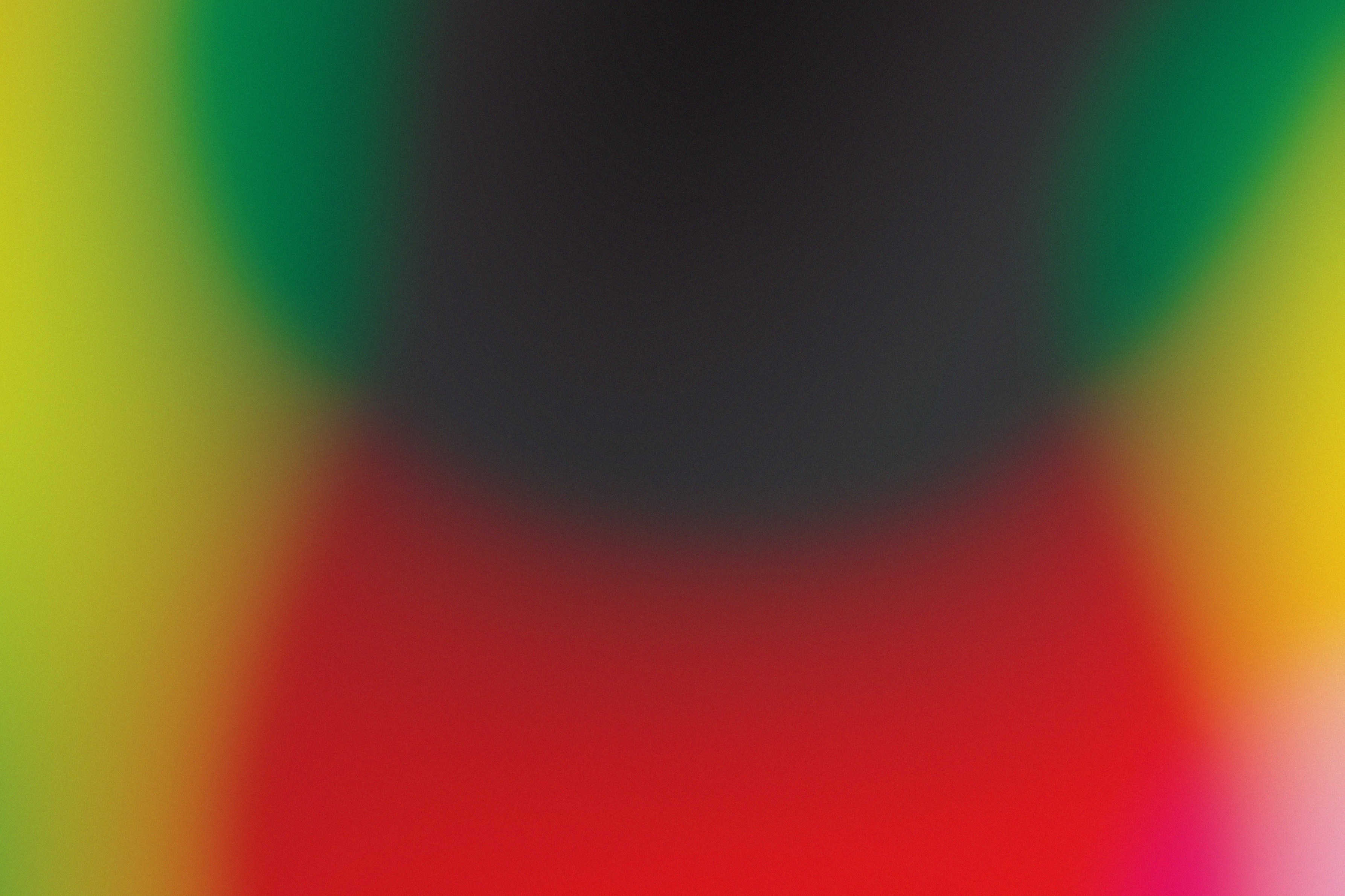 A soft abstract gradient of blurred red, green, yellow, and dark grey