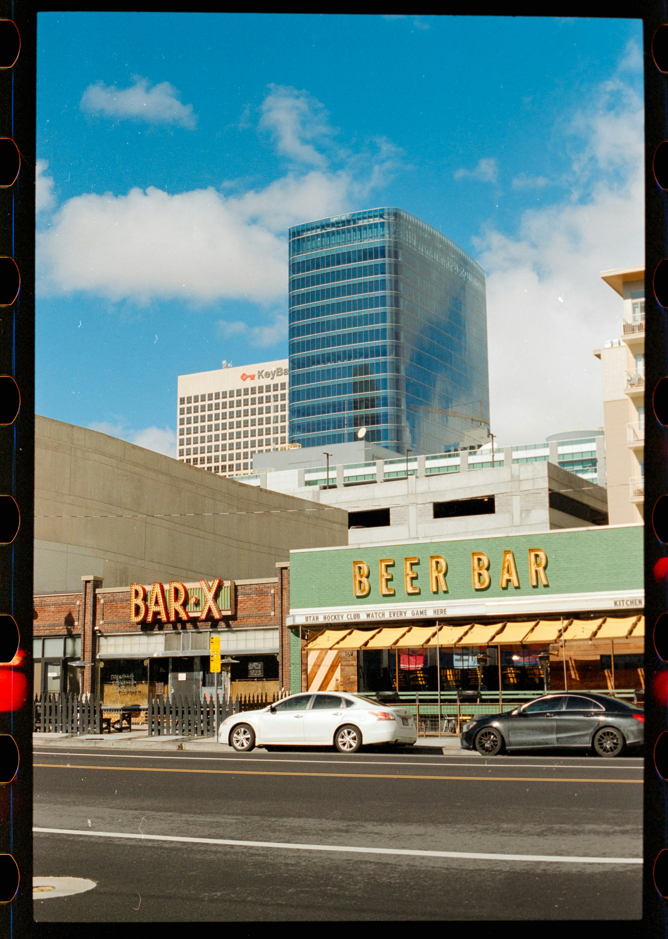 Bar X and Beer Bar storefronts with cars parked on a city street