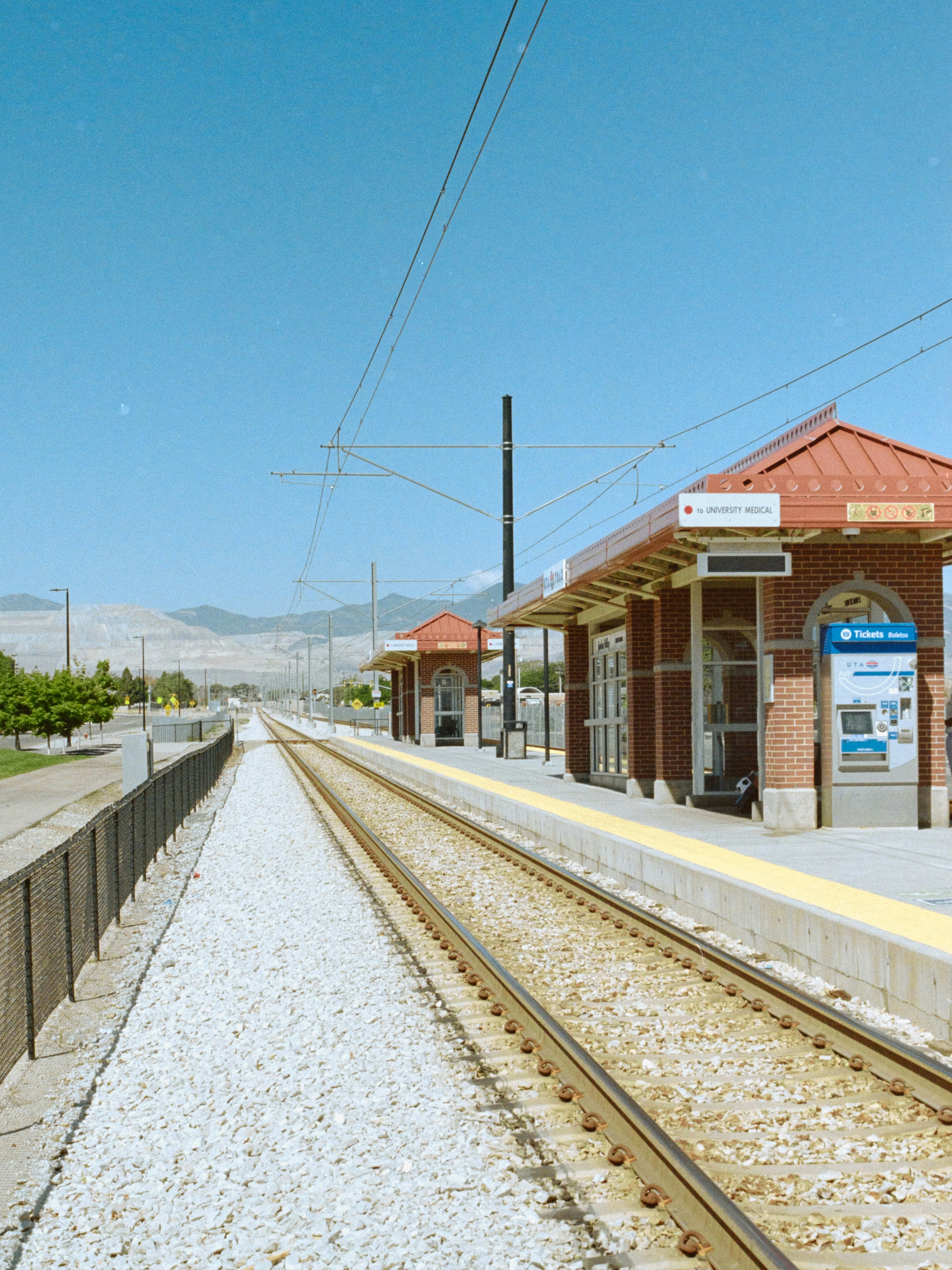 A light rail station with brick shelters and a ticket machine under a blue sky