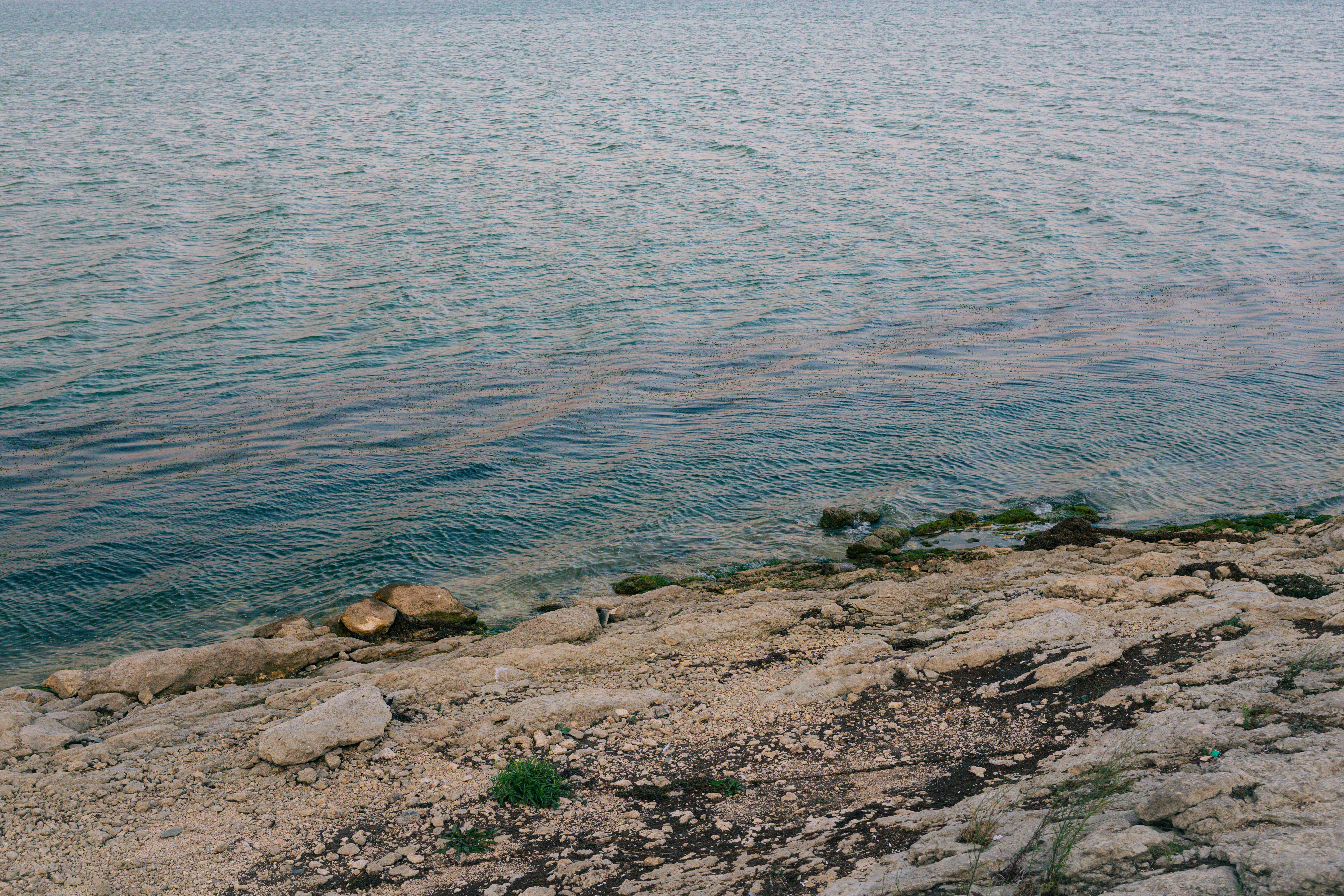 A rocky shoreline meeting the calm blue water of a sea
