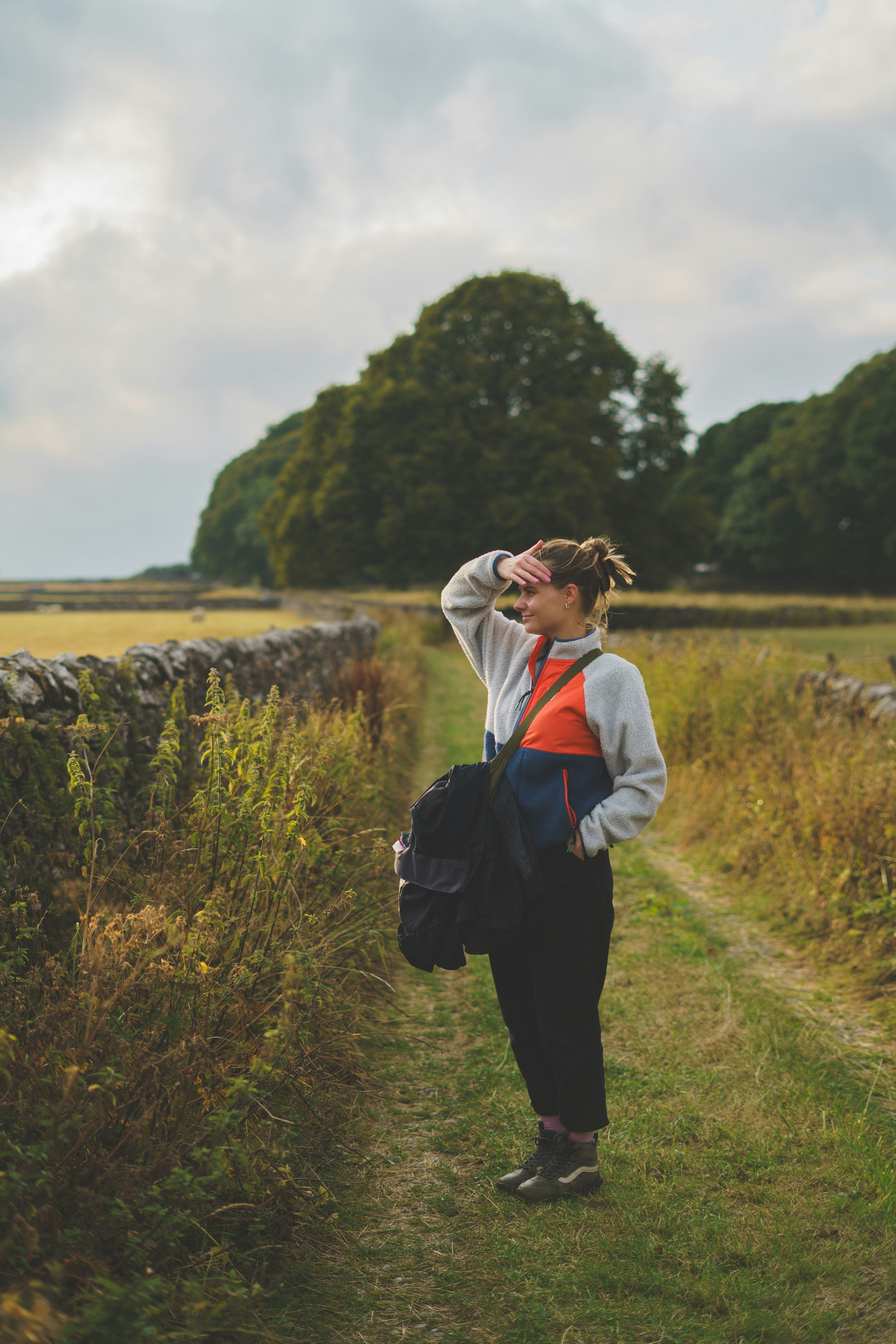 A woman in a fleece jacket shielding her eyes on a rural path